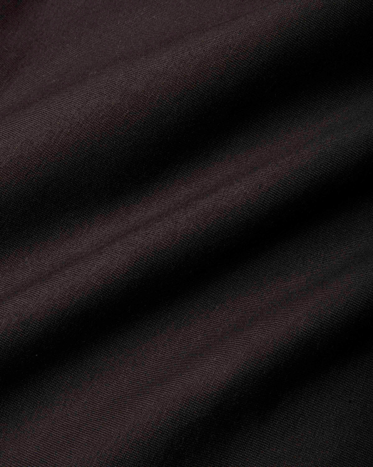 A close-up of dark, draped fabric with a fine ribbed texture, showing soft folds and shadows.