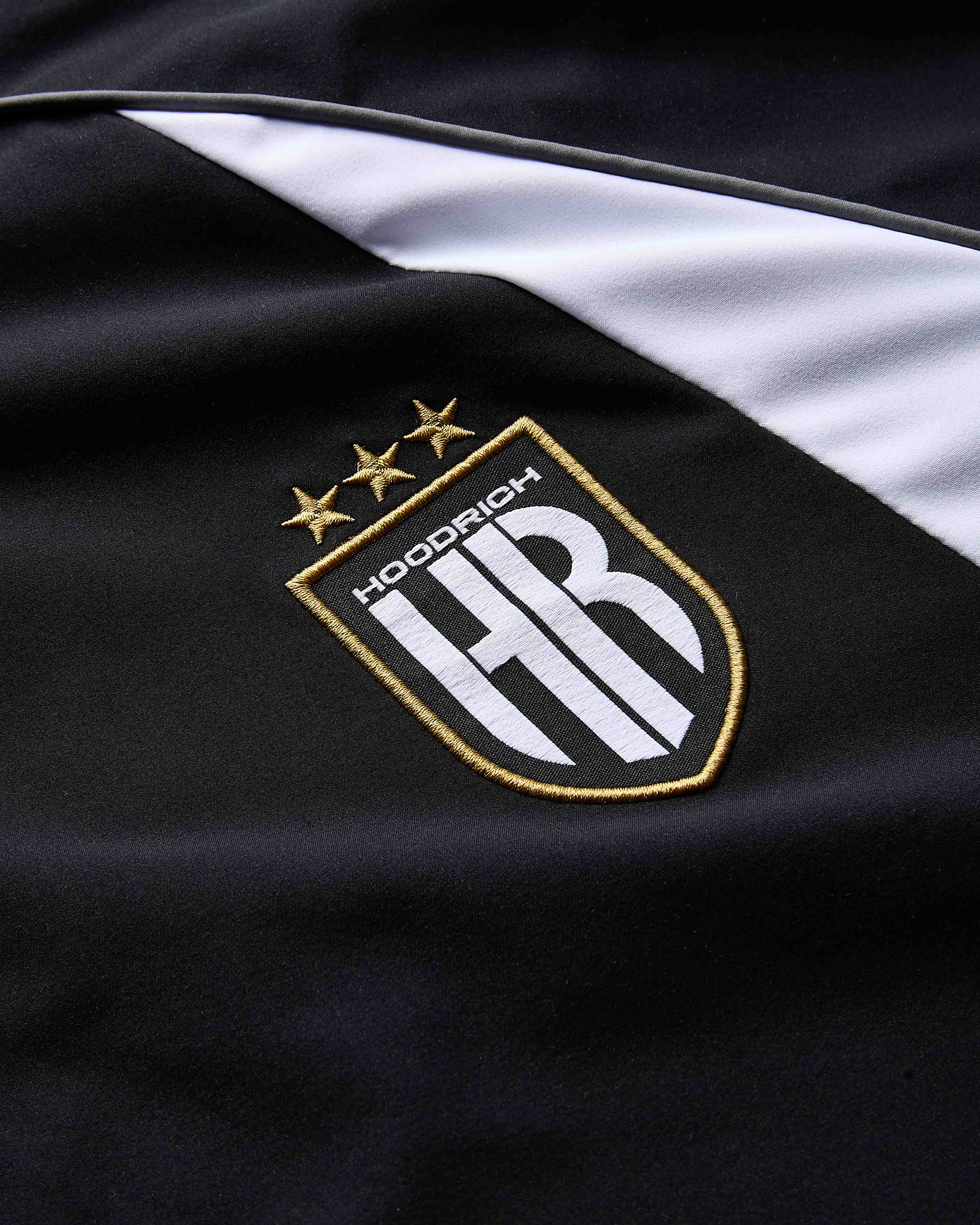 Close-up of a black and white jacket with a logo featuring 'HR' and stars on a dark background.