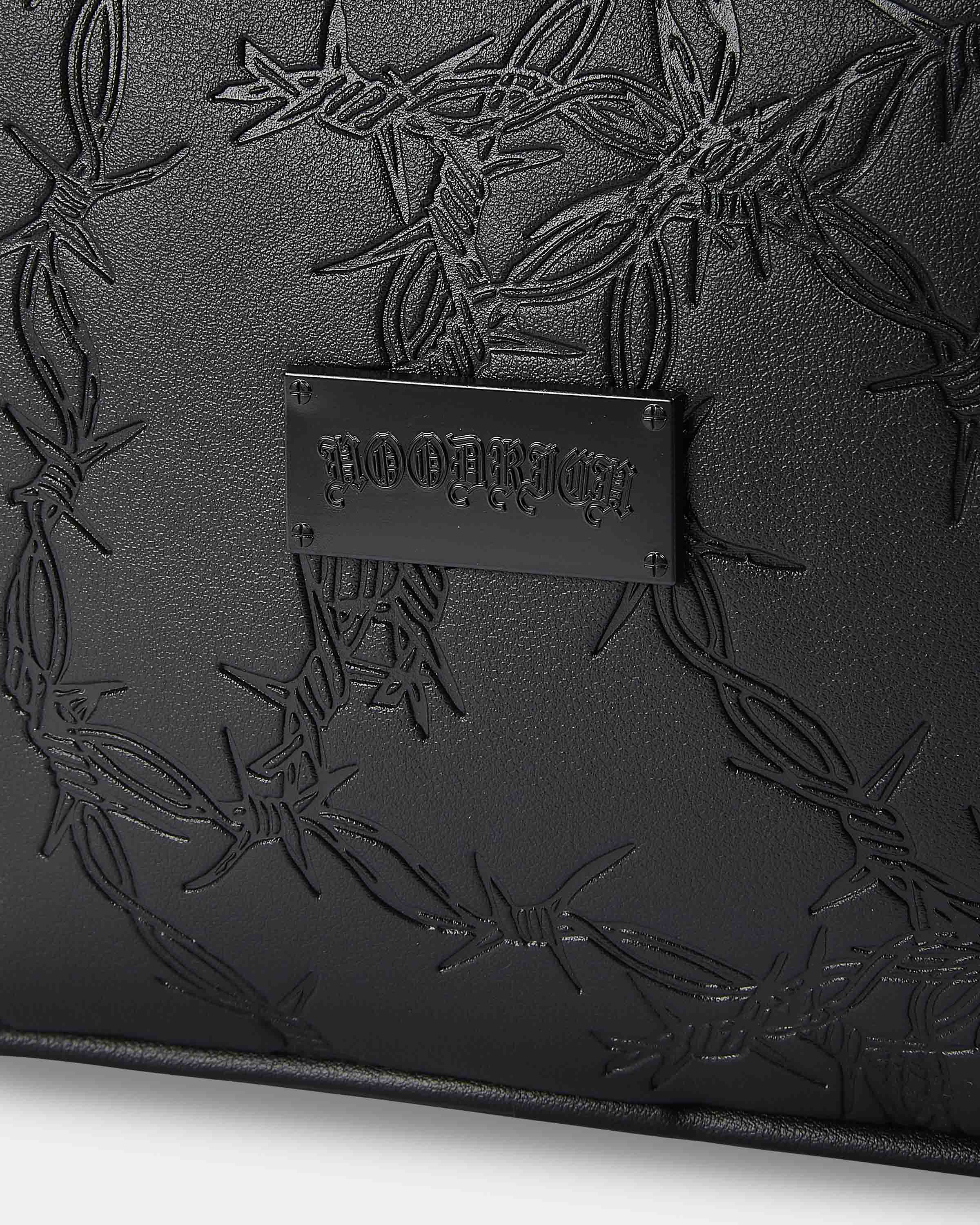 Black leather clutch with embossed design and visible brand name on a white background