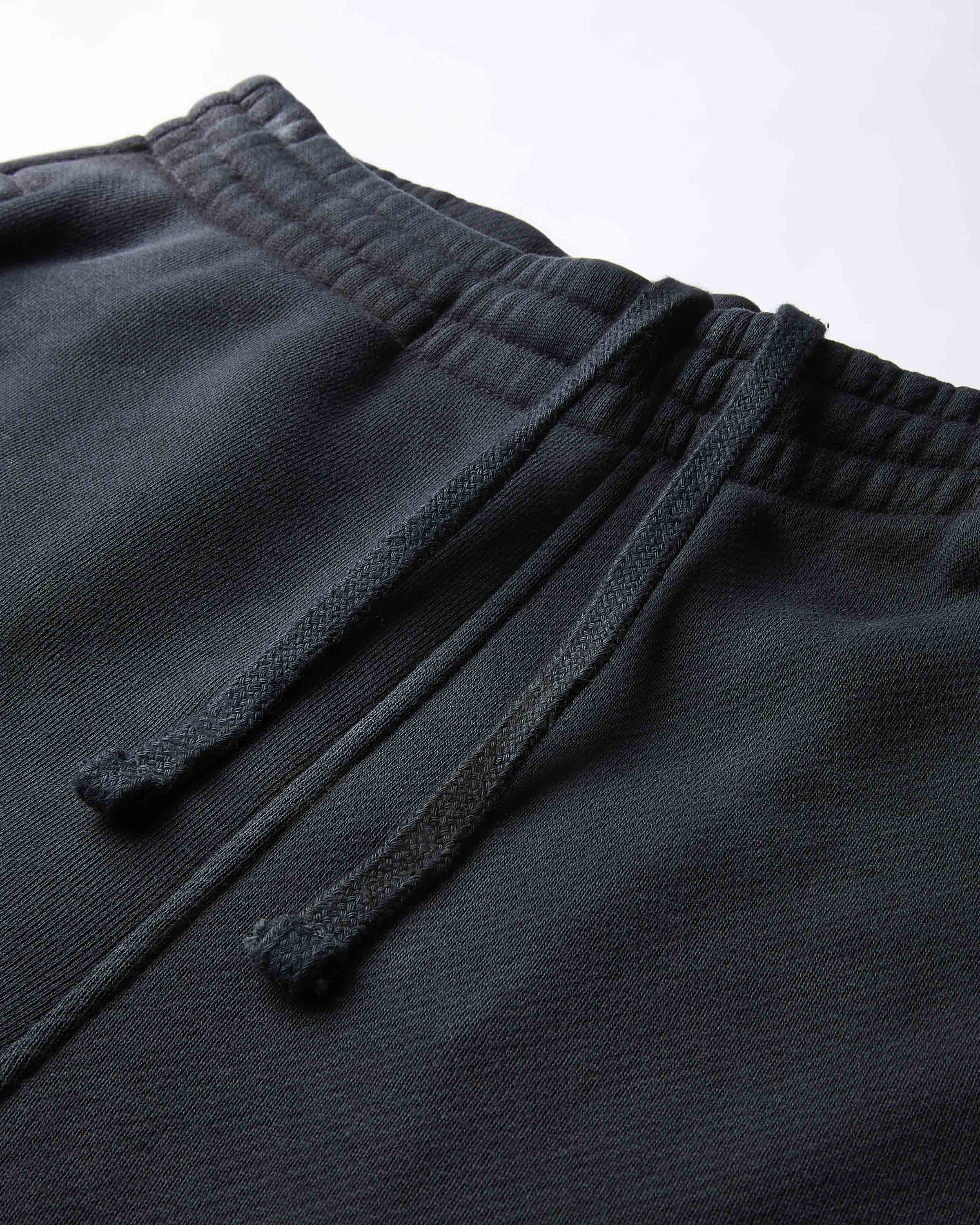 Close-up of dark gray sweatpants with drawstring on a light gray background