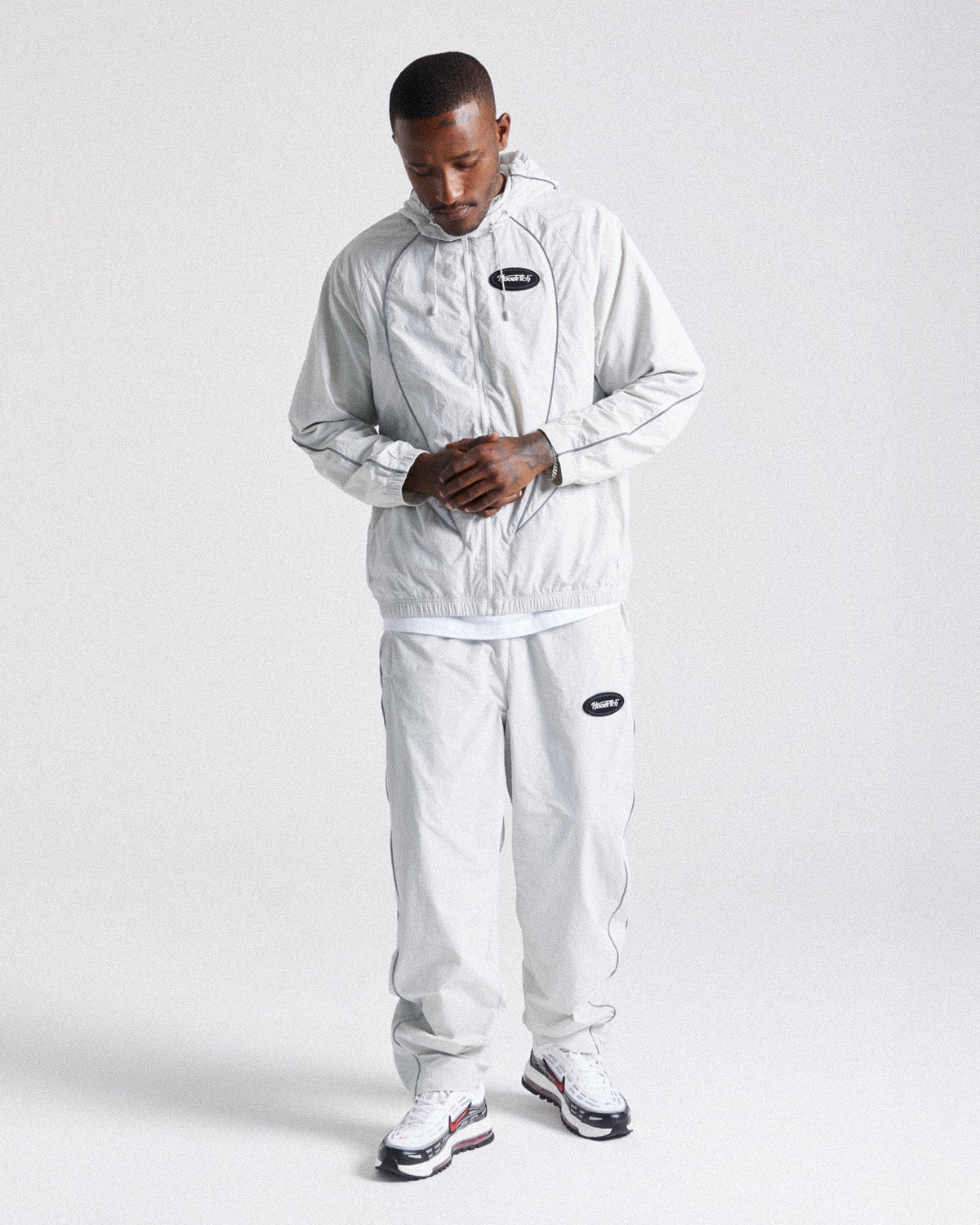 Displays a model wearing the Grey 'Hoodrich' branded men's Cypher Woven Full Tracksuit