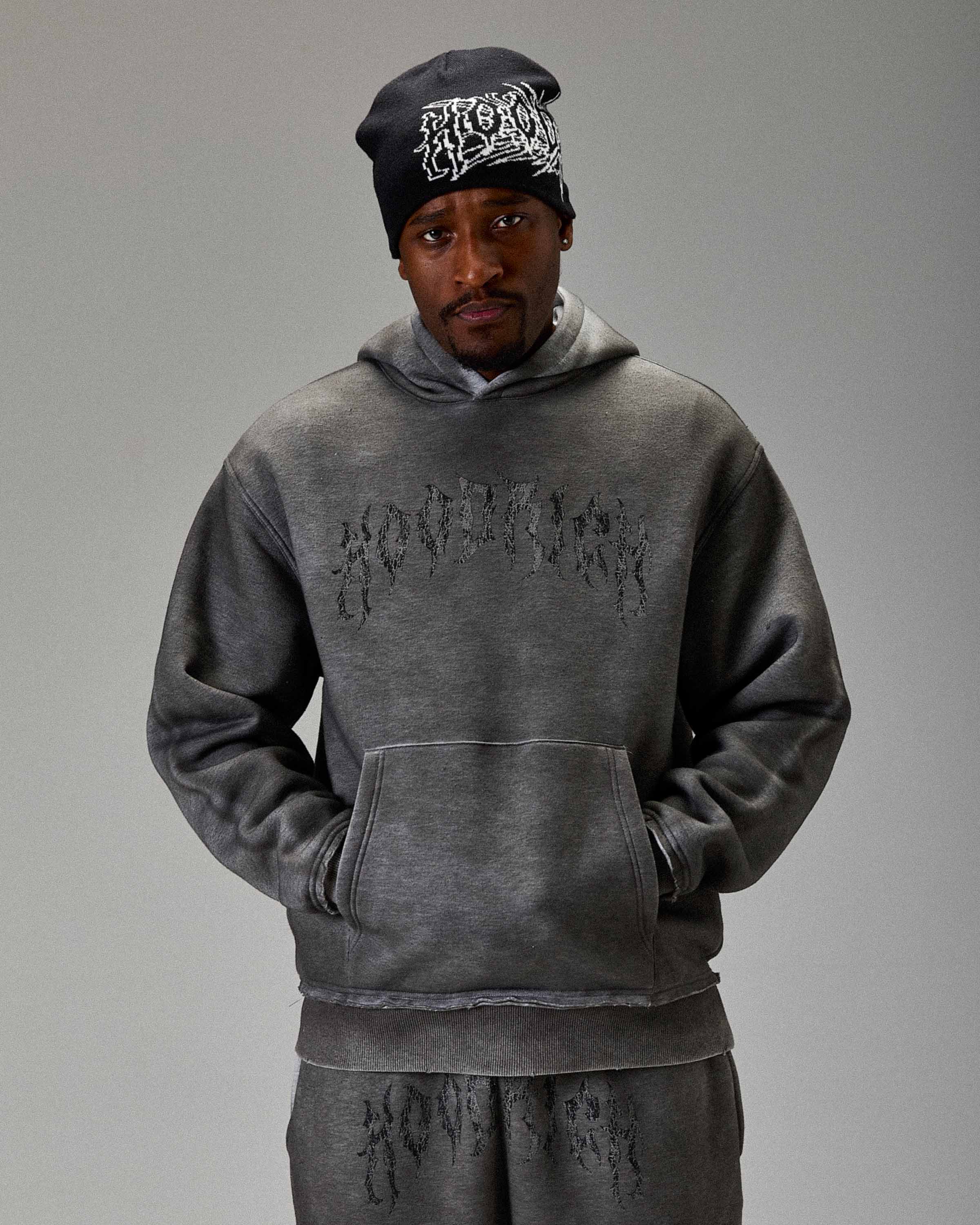 Displays a model wearing the Grey 'Hoodrich' branded men's The Winner's Circle Hazy Full Tracksuit