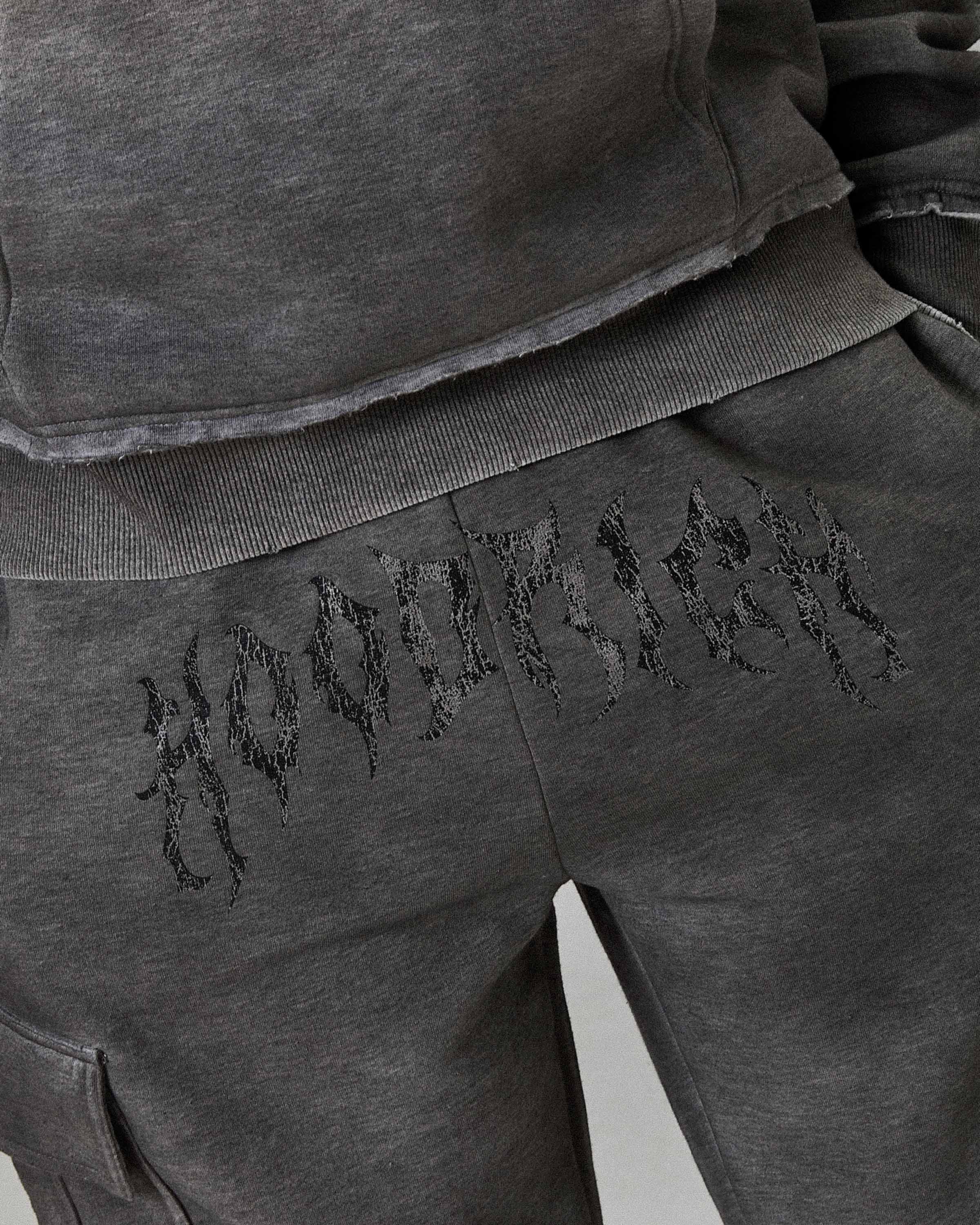 Gray sweatshirt and pants with embroidered text on a plain background