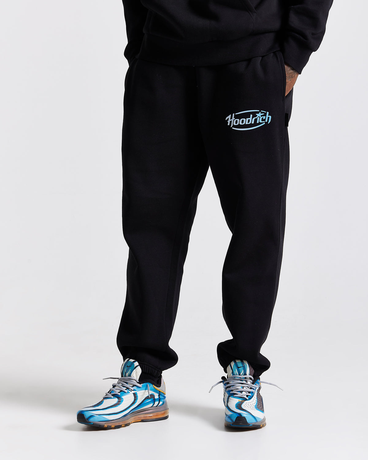 Displays a model wearing the Black 'Hoodrich' branded men's Curve Full Tracksuit