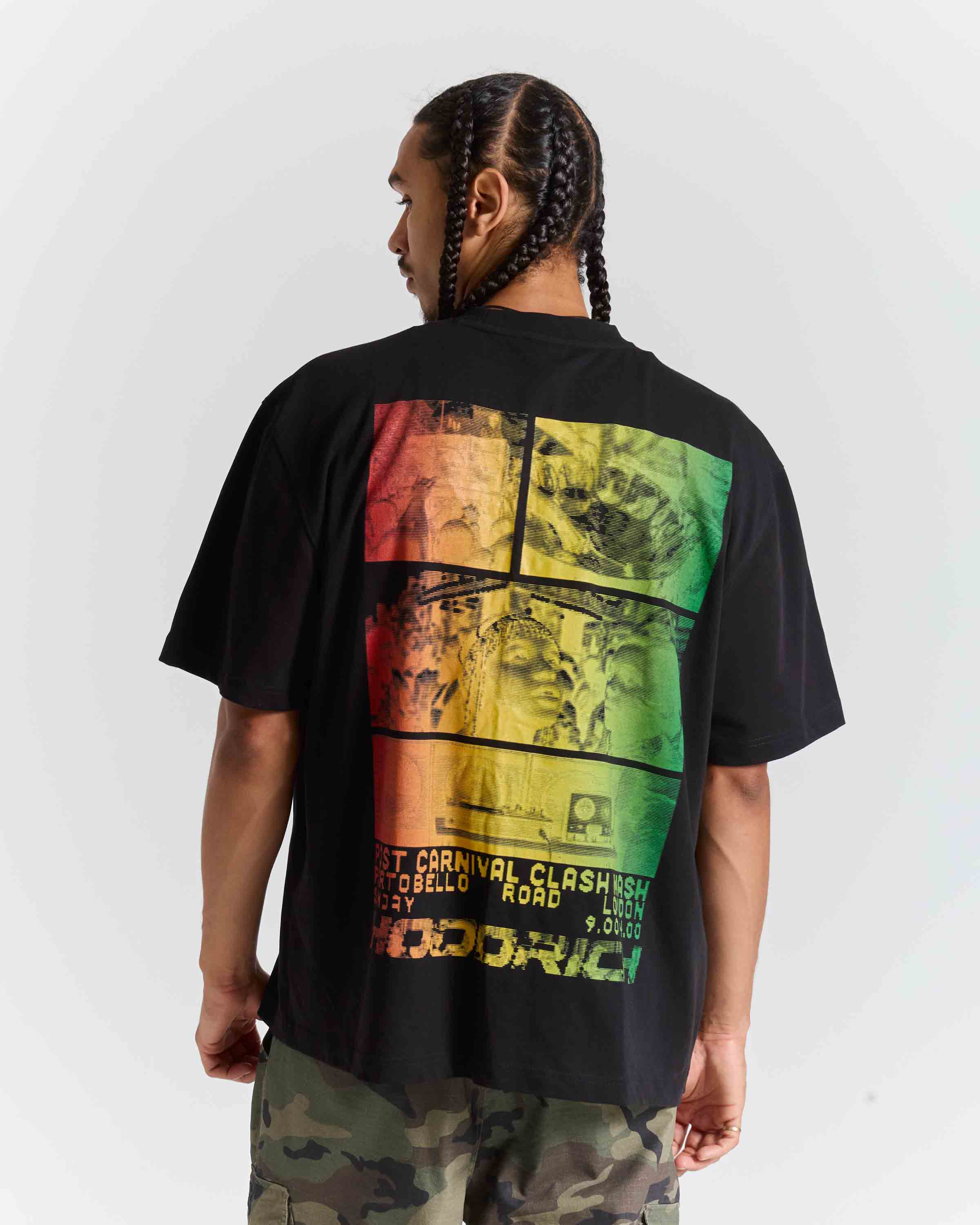A man shown from the back wearing a black t-shirt with a large, colorful graphic print on the back in red, orange, yellow, and green. The shirt features text including 'BEST CARNIVAL CLOSETED IN MY ROOSTER' and 'RODRIGO'.