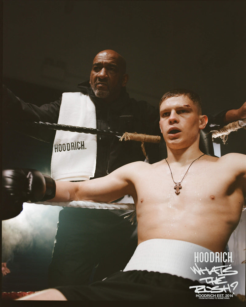 Boxer in a boxing ring with a coach and 'Hoodrich' branding on a towel.