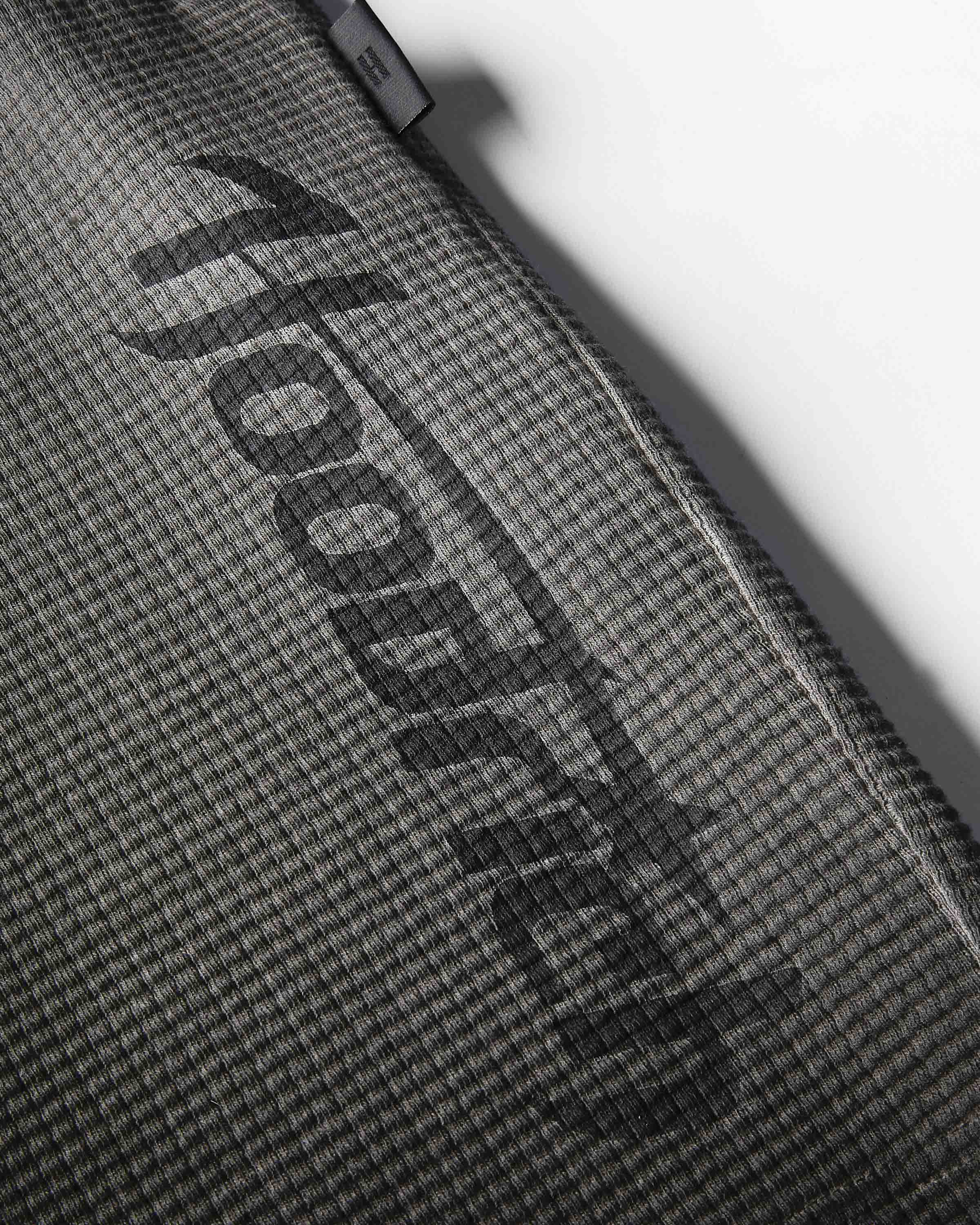 Close-up of a dark gray textured fabric surface with a large black diagonal 'hoodedog' logo and a small black brand tab near the top edge.