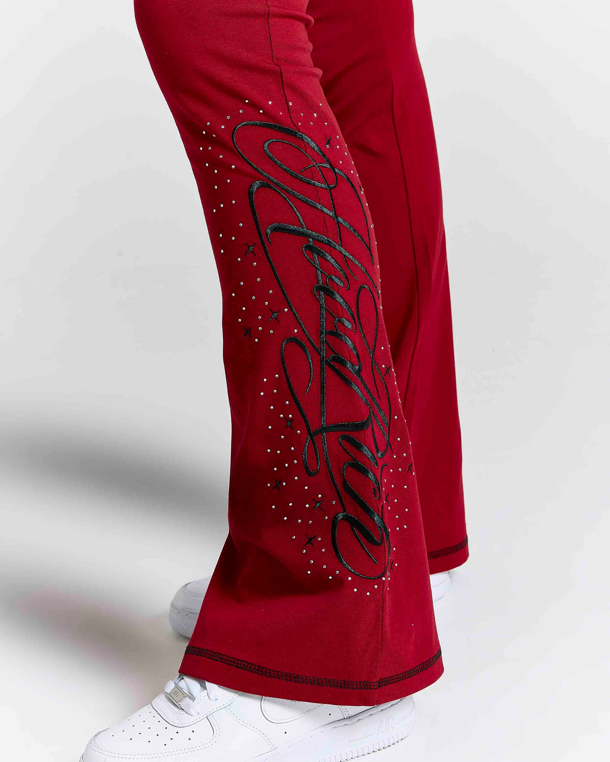 Displays a model wearing the Red 'Hoodrich' branded women's Gleam Full Tracksuit featuring the details on the branding 