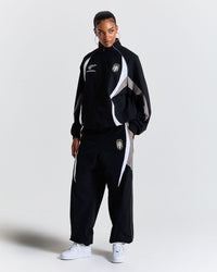 Person wearing a black tracksuit with white and gray accents on a light gray background