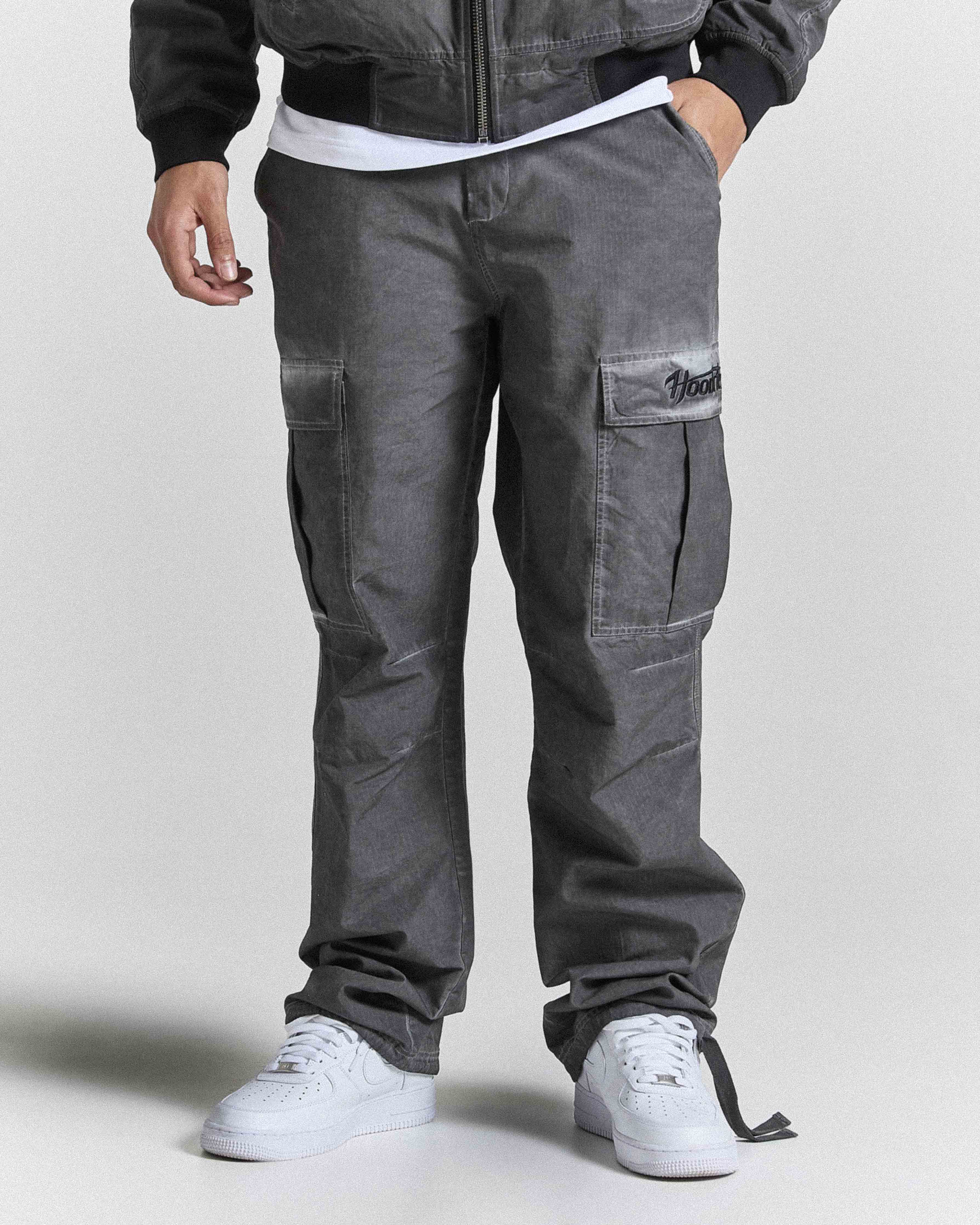 Person wearing gray cargo pants with a plain background