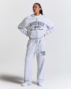 Person wearing a gray 'Hoodrich' tracksuit on a white background