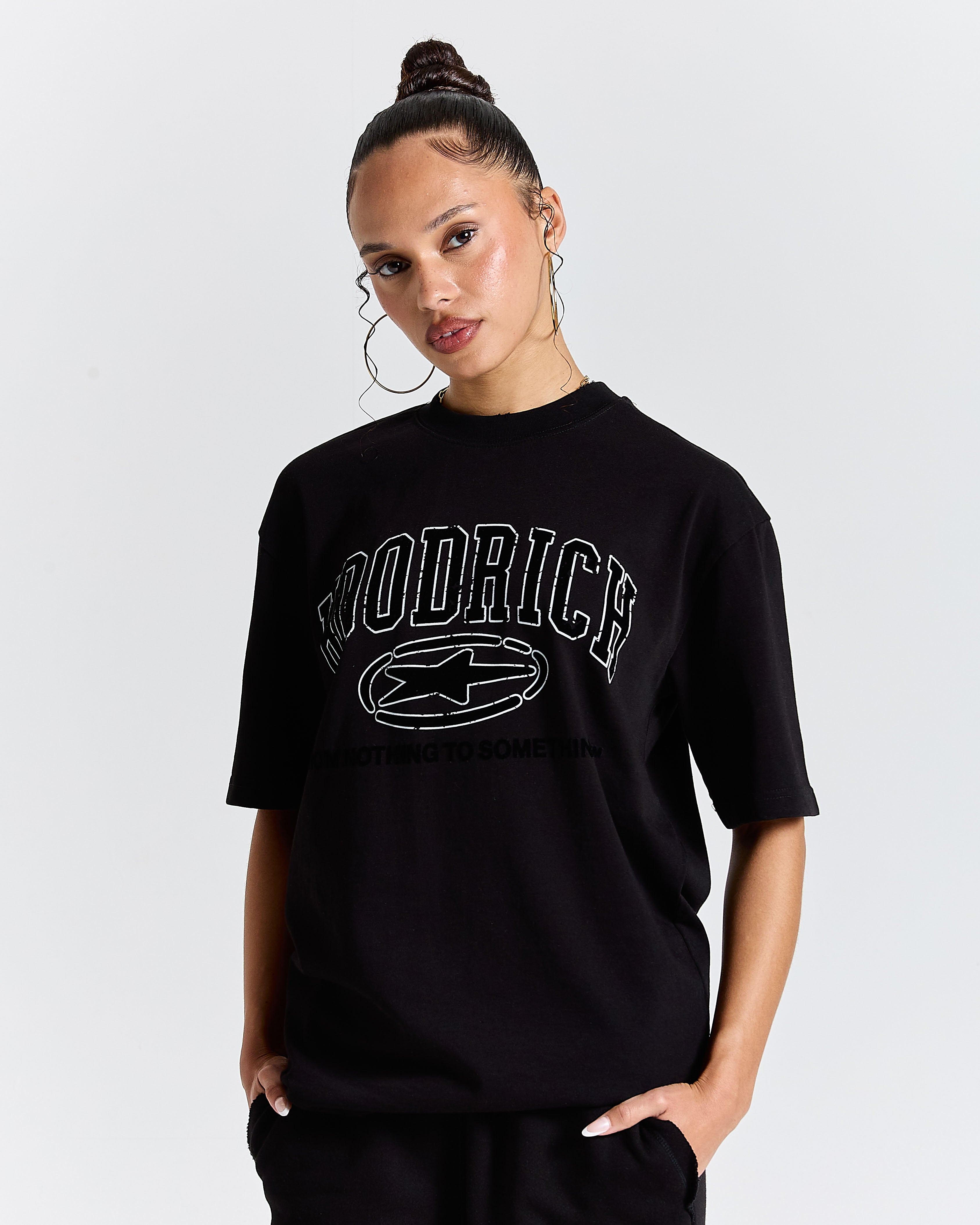 Person wearing a black t-shirt with a logo and text on a plain background