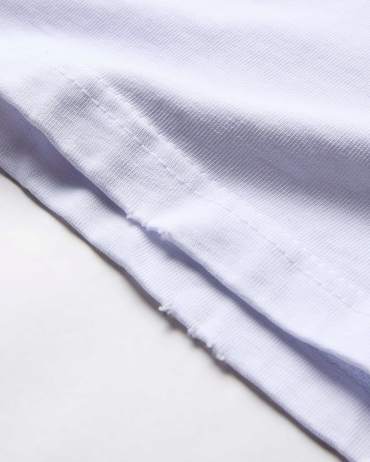 Extreme close-up of the textured white fabric on a Hoodrich t-shirt.