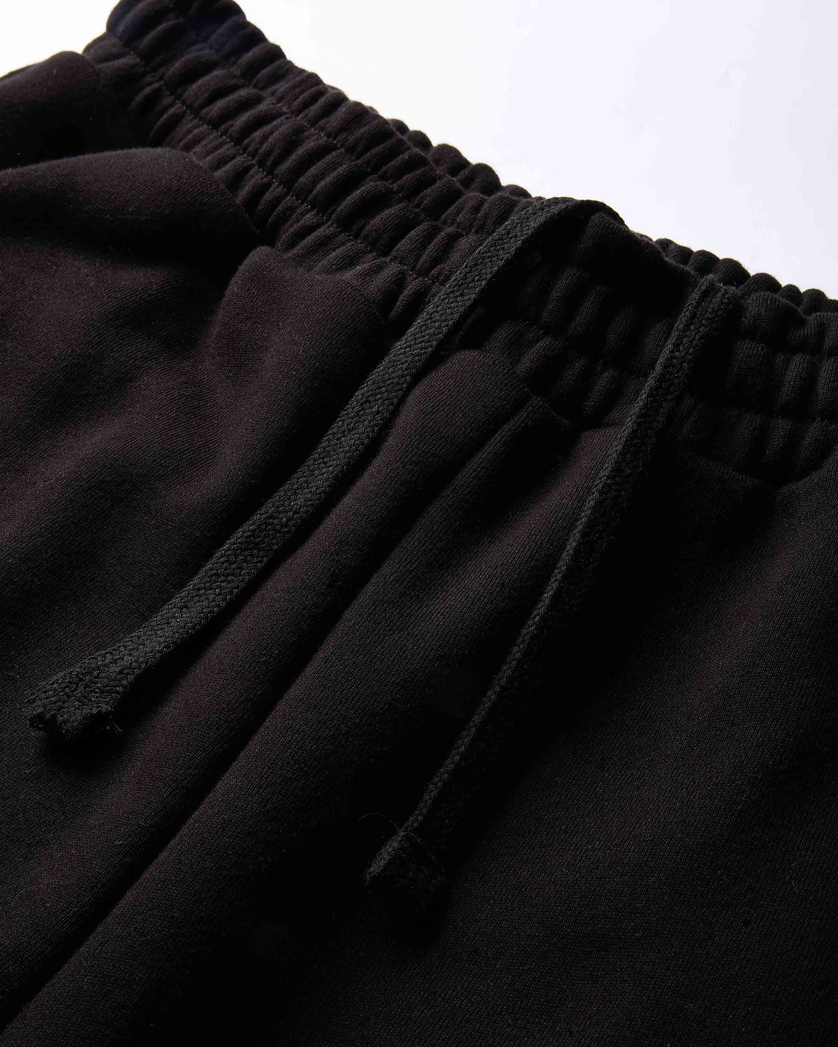 Close-up of black drawstring sweatpants showing the elastic waistband and fabric texture.