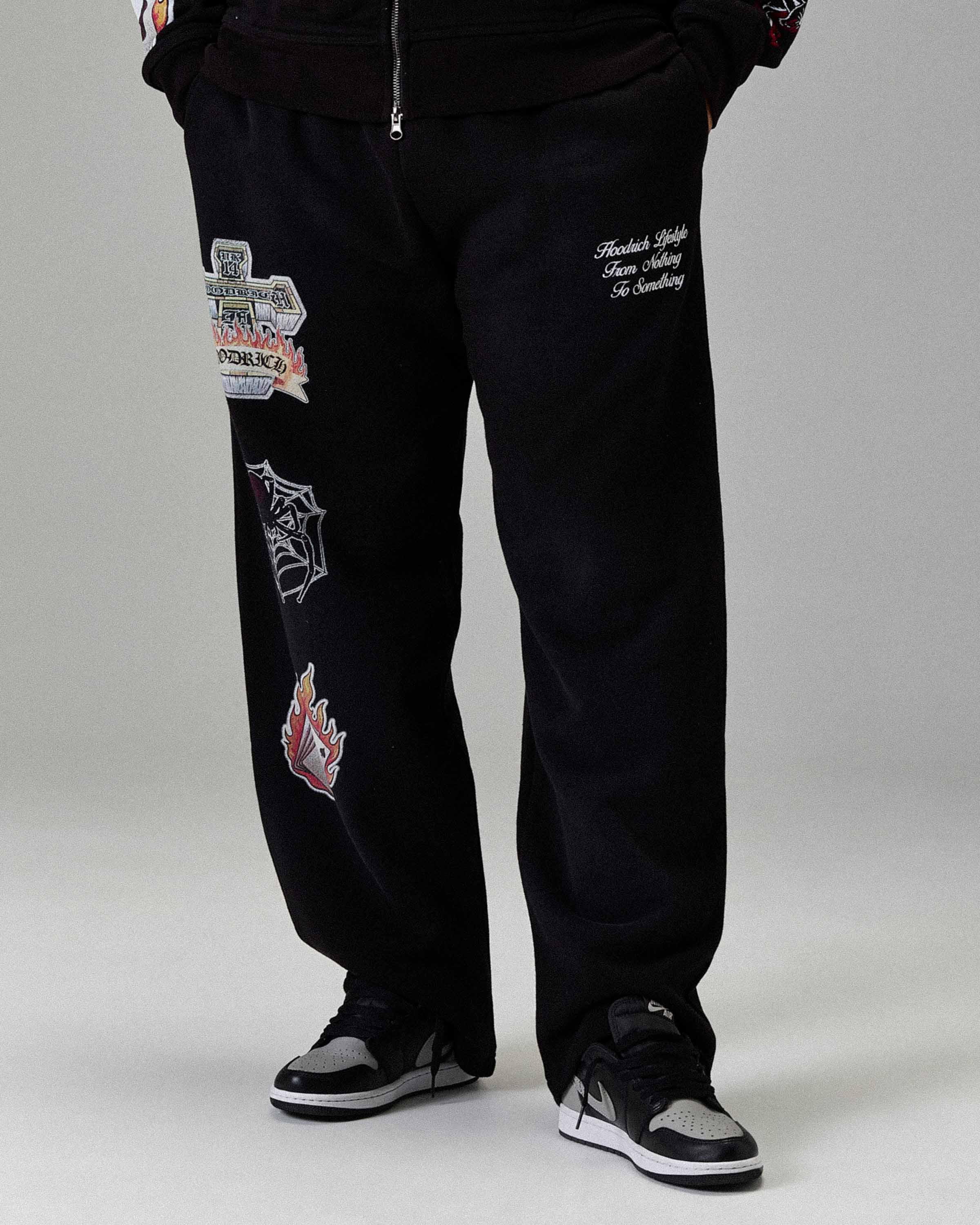 Black pants with various patches on a plain background