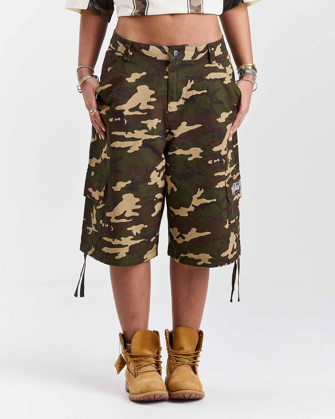 Person wearing camouflage shorts and brown boots on a white background