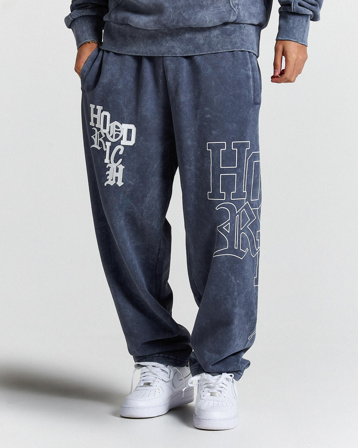 Person wearing blue sweatpants with 'HOODRICH' text on a light gray background