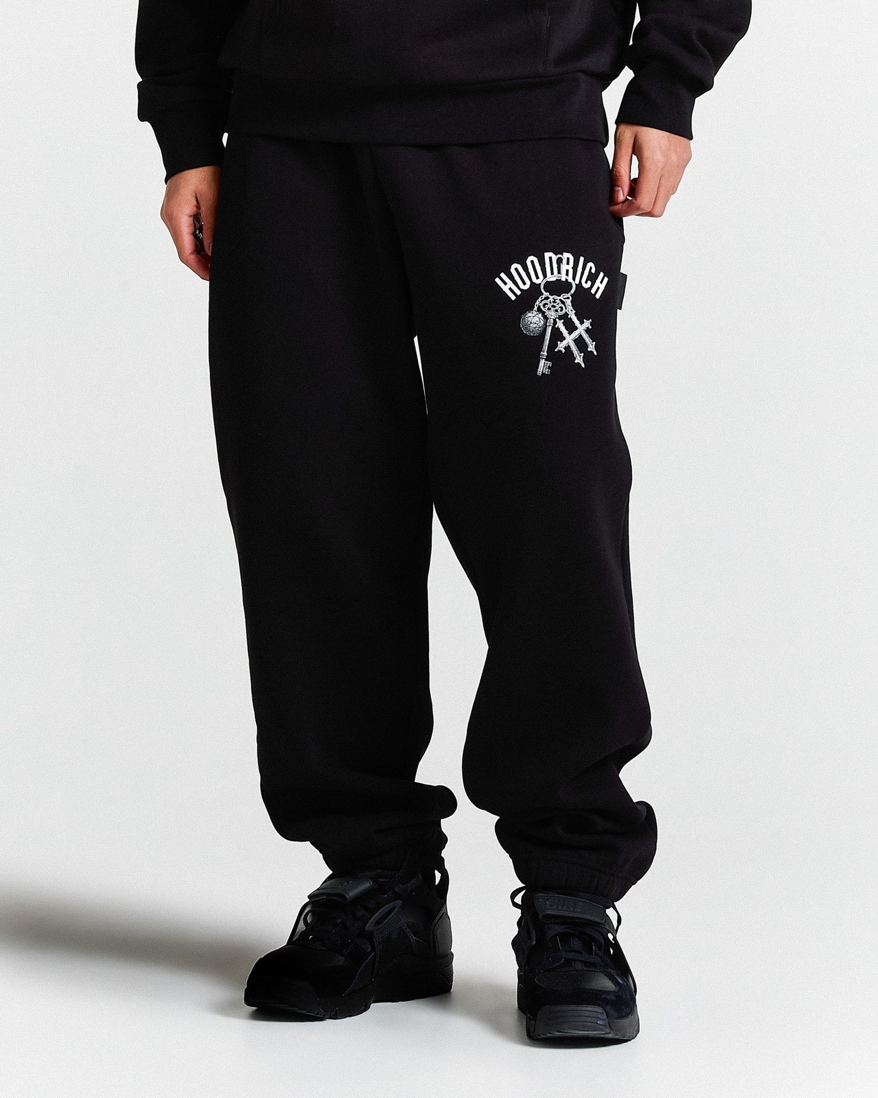 Person wearing black sweatpants with a logo on a white background