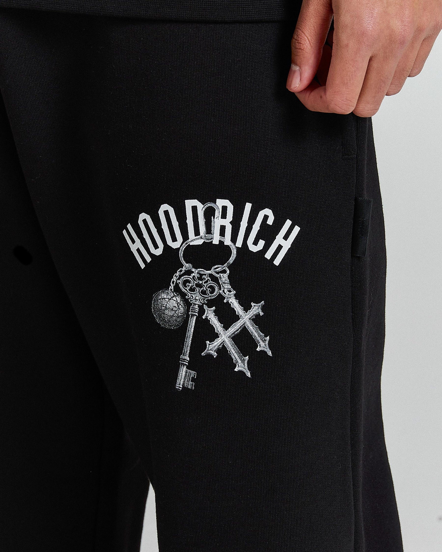 Black sweatpants with 'Hoodrich' logo featuring keys on a plain background