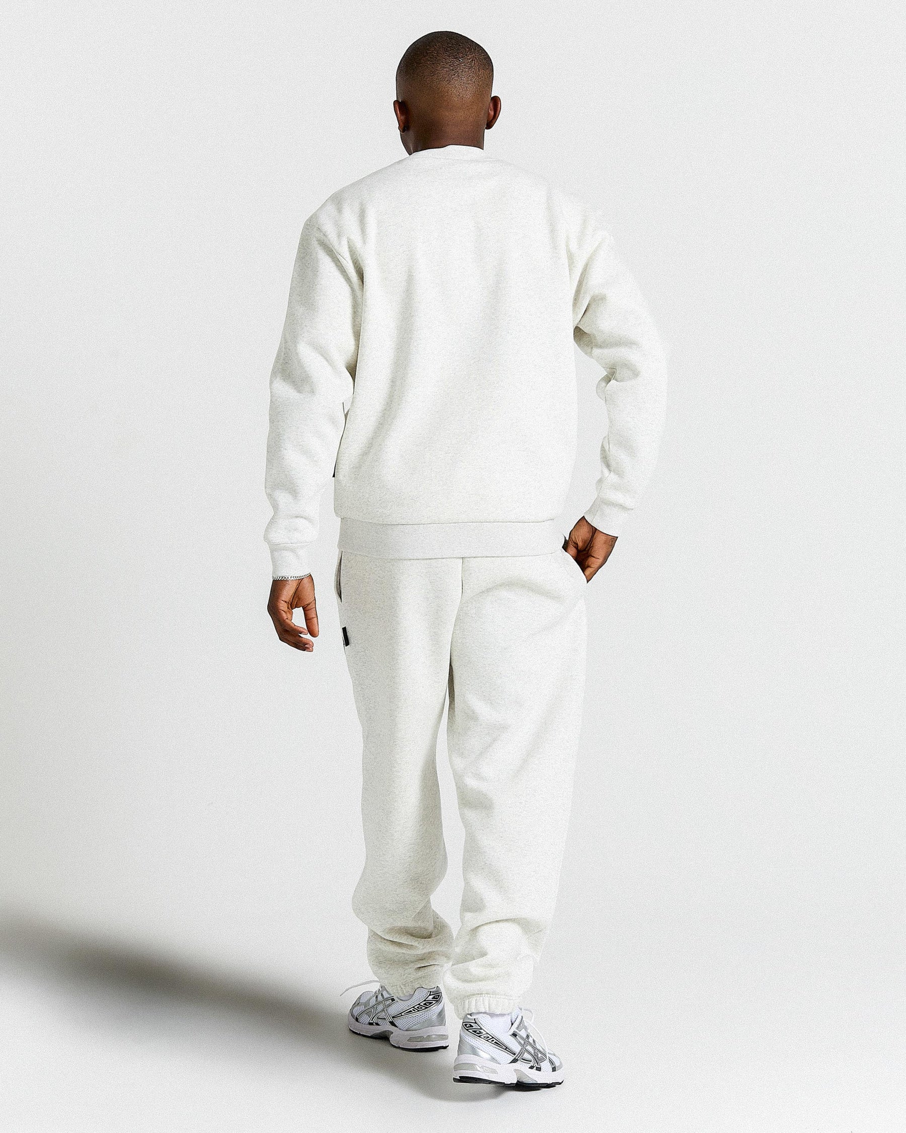 Person wearing a light grey tracksuit on a plain background