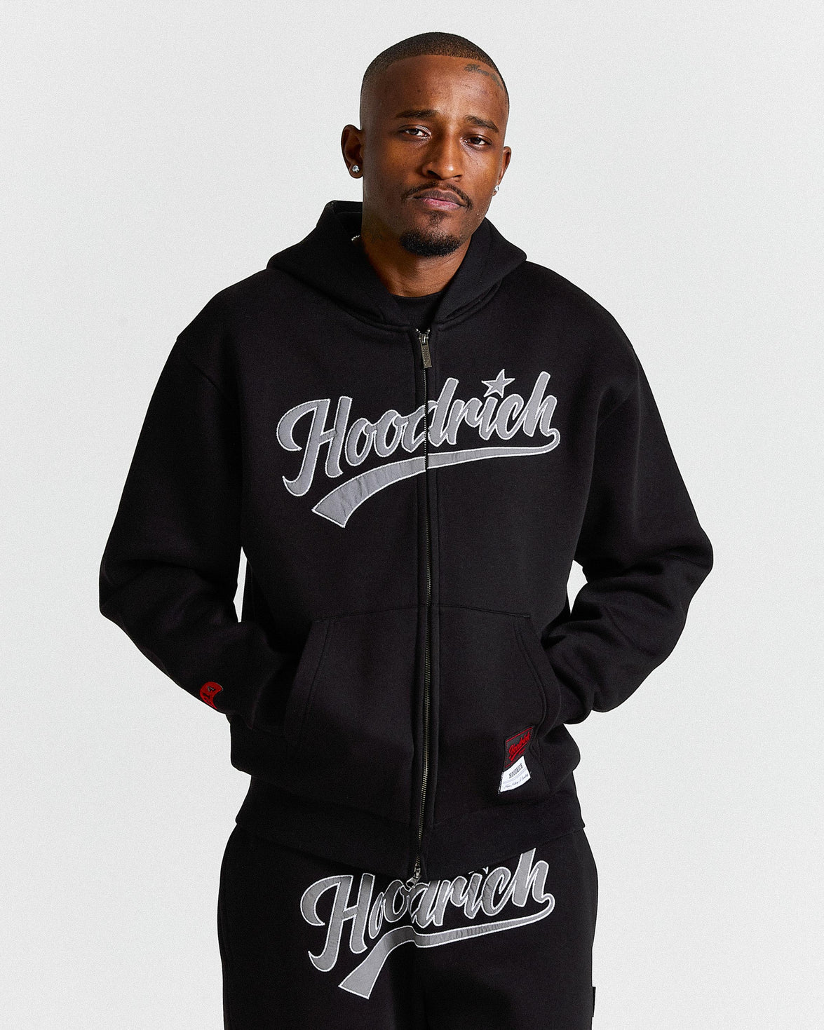Man wearing a black hoodie with 'Hoodrich' logo on a light gray background