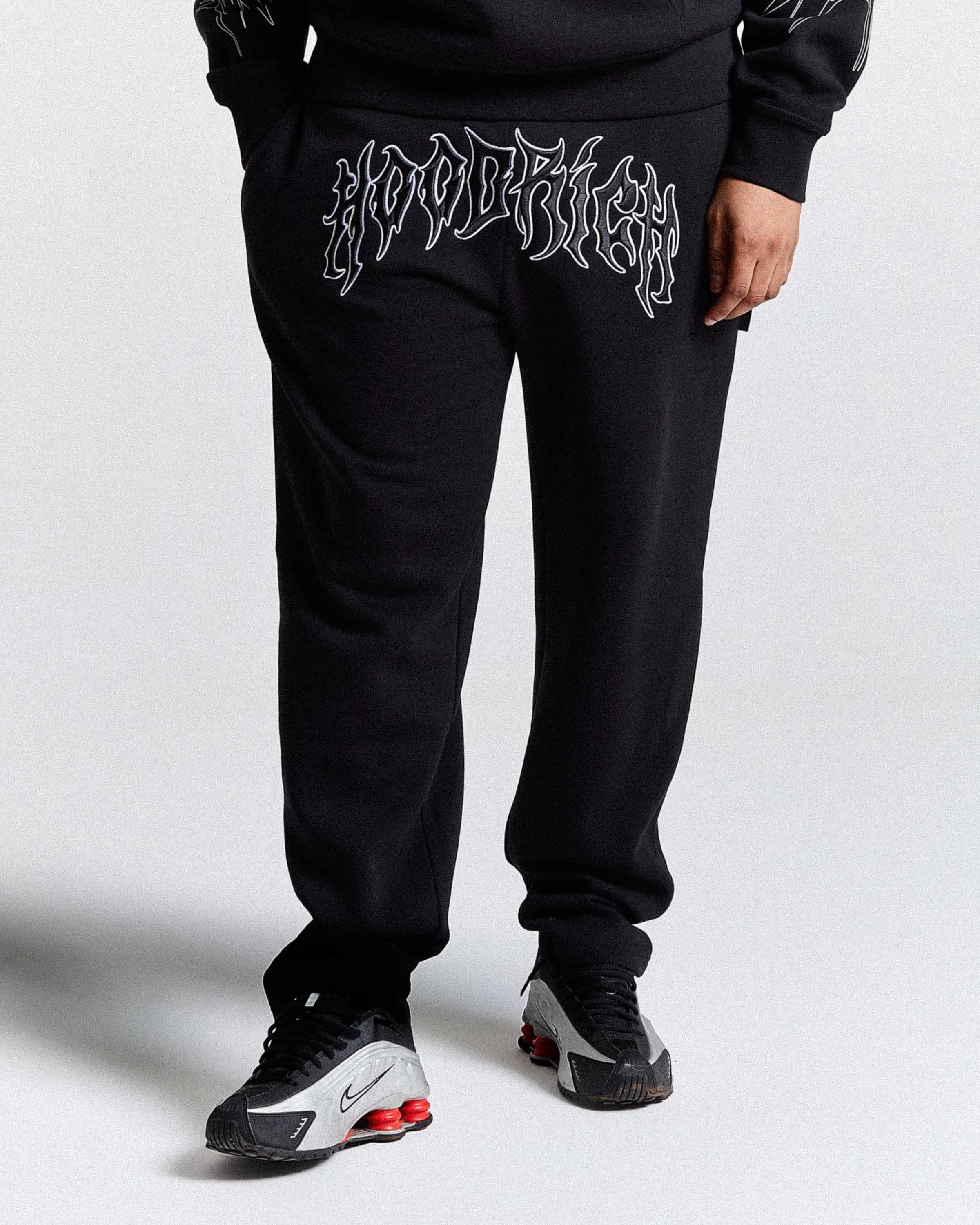 Person wearing black sweatpants with white text design on a plain background