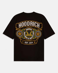 A black short-sleeve t-shirt with a large graphic print on the front. The graphic features the brand name 'HOODRICH' in white letters inside a gold-bordered arch, with circular medallions containing gold stars and a central gold double-horns emblem, and 'EST 2014.