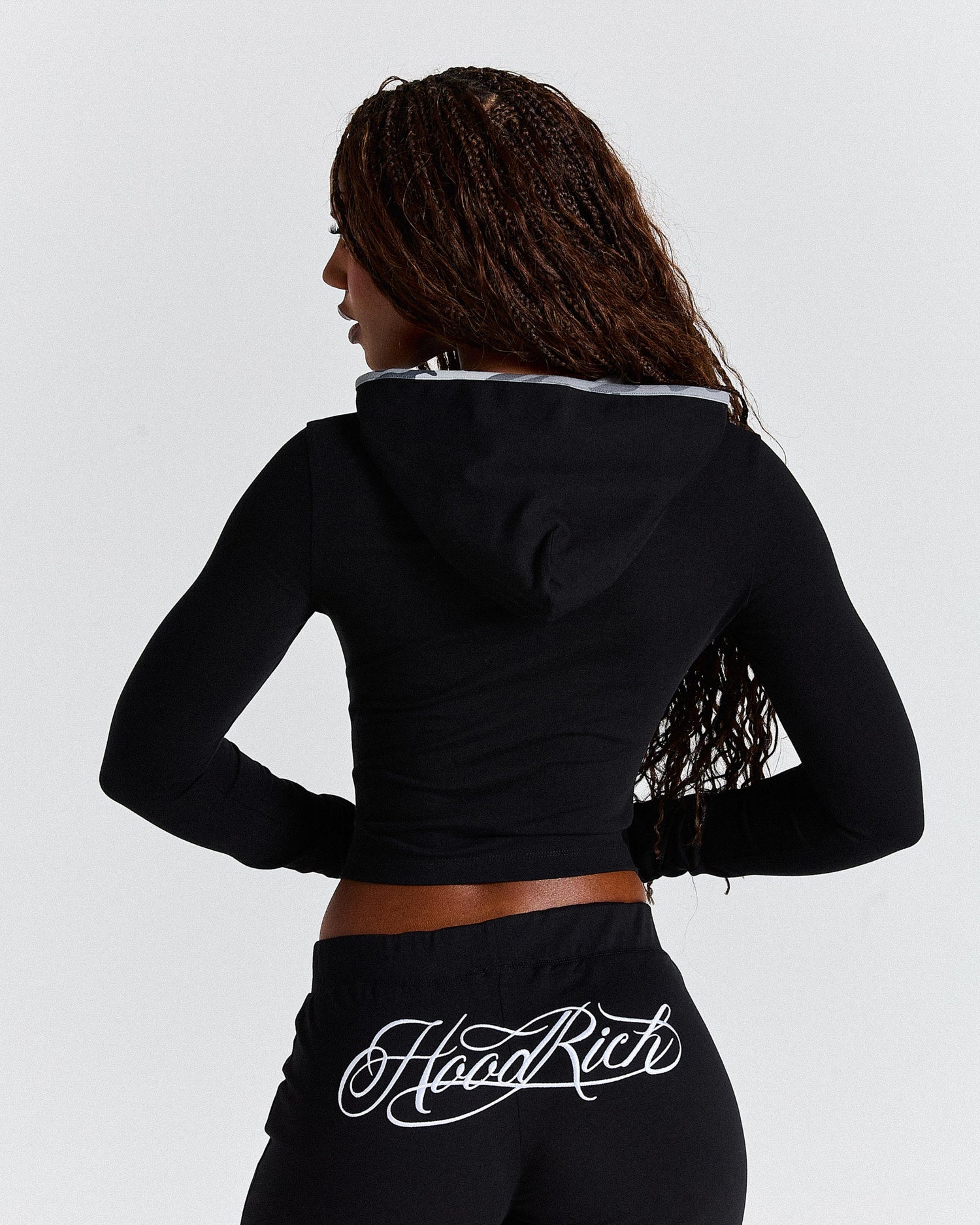 Person wearing a black hoodie with 'Hoodrich' branding on a light grey background