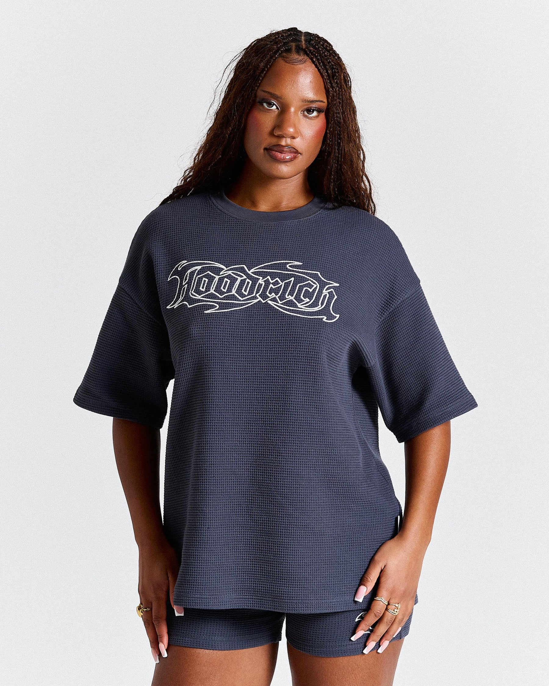 Woman wearing a navy oversized t-shirt with a logo on a white background