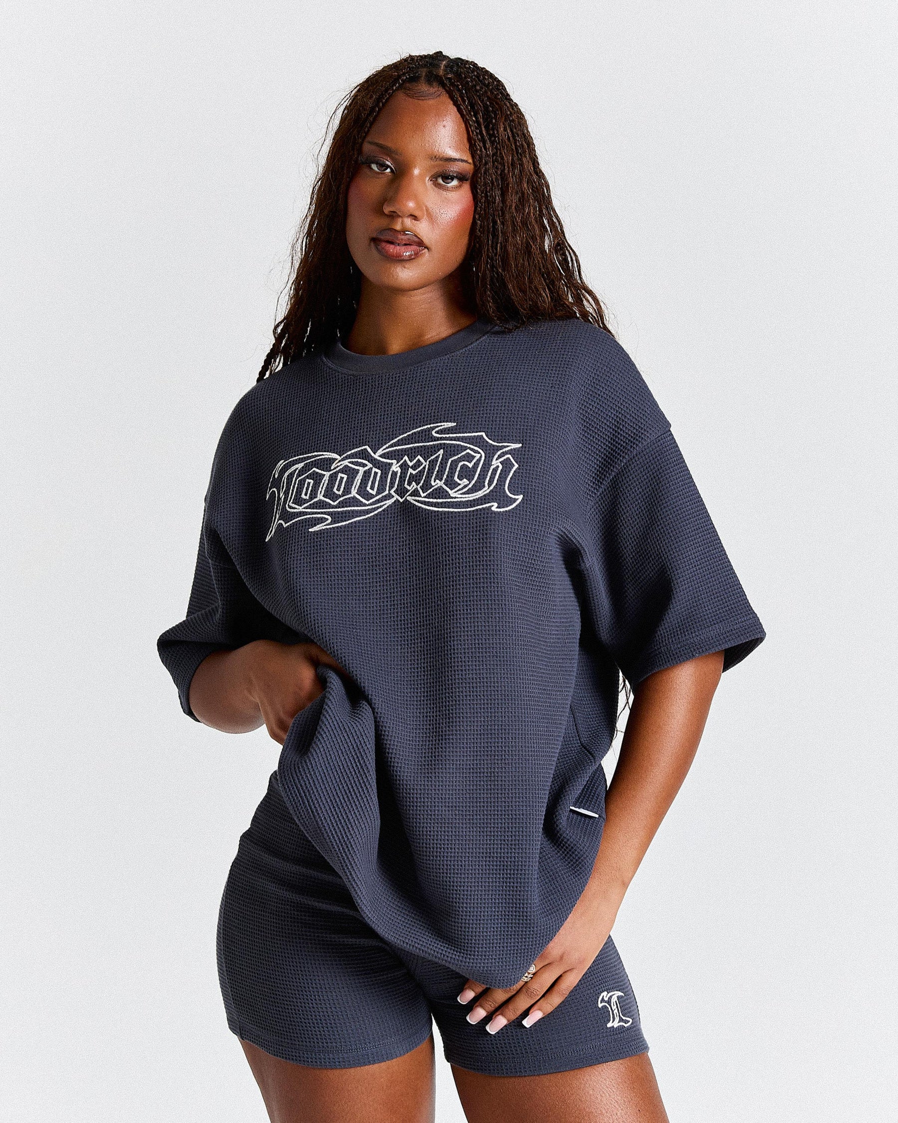 Woman wearing a navy oversized t-shirt with a logo on a light gray background