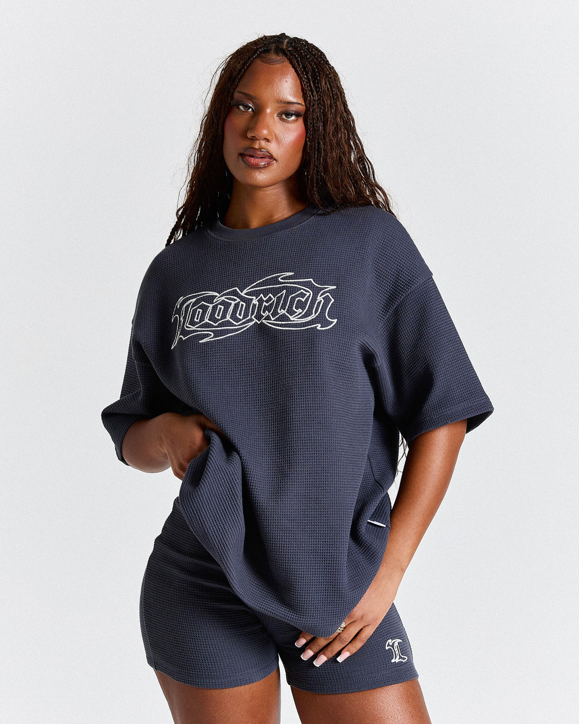 Woman wearing a navy oversized t-shirt with a logo on a light gray background