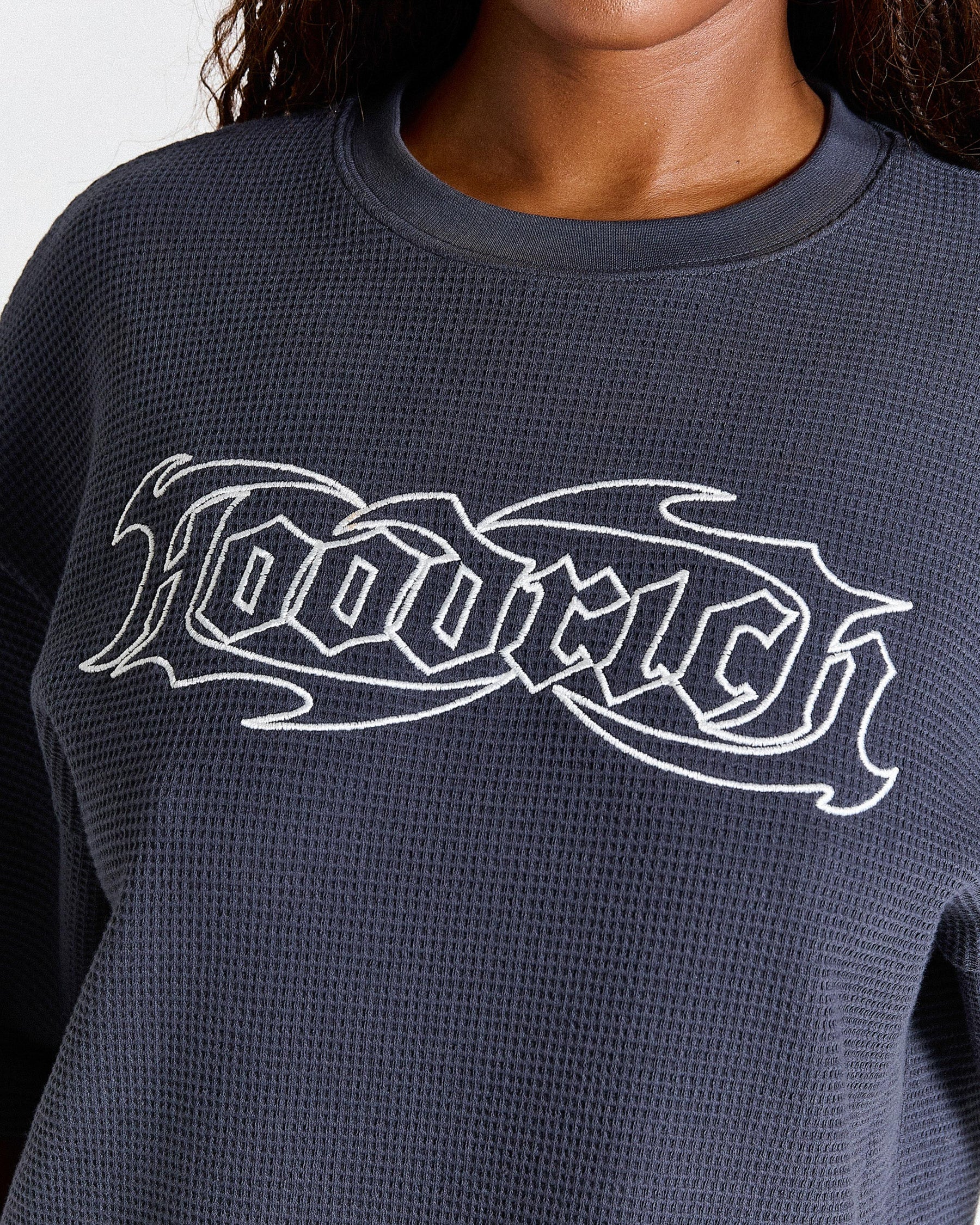 Navy blue sweatshirt with white logo worn by a person