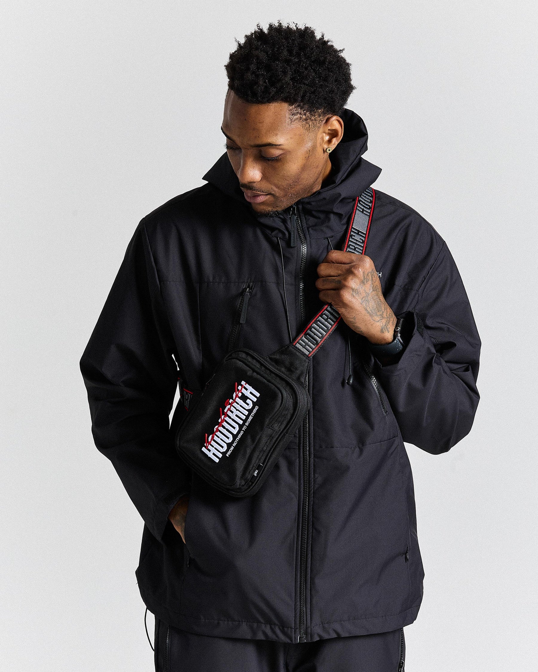 Man wearing a black jacket with a visible brand logo on a white background