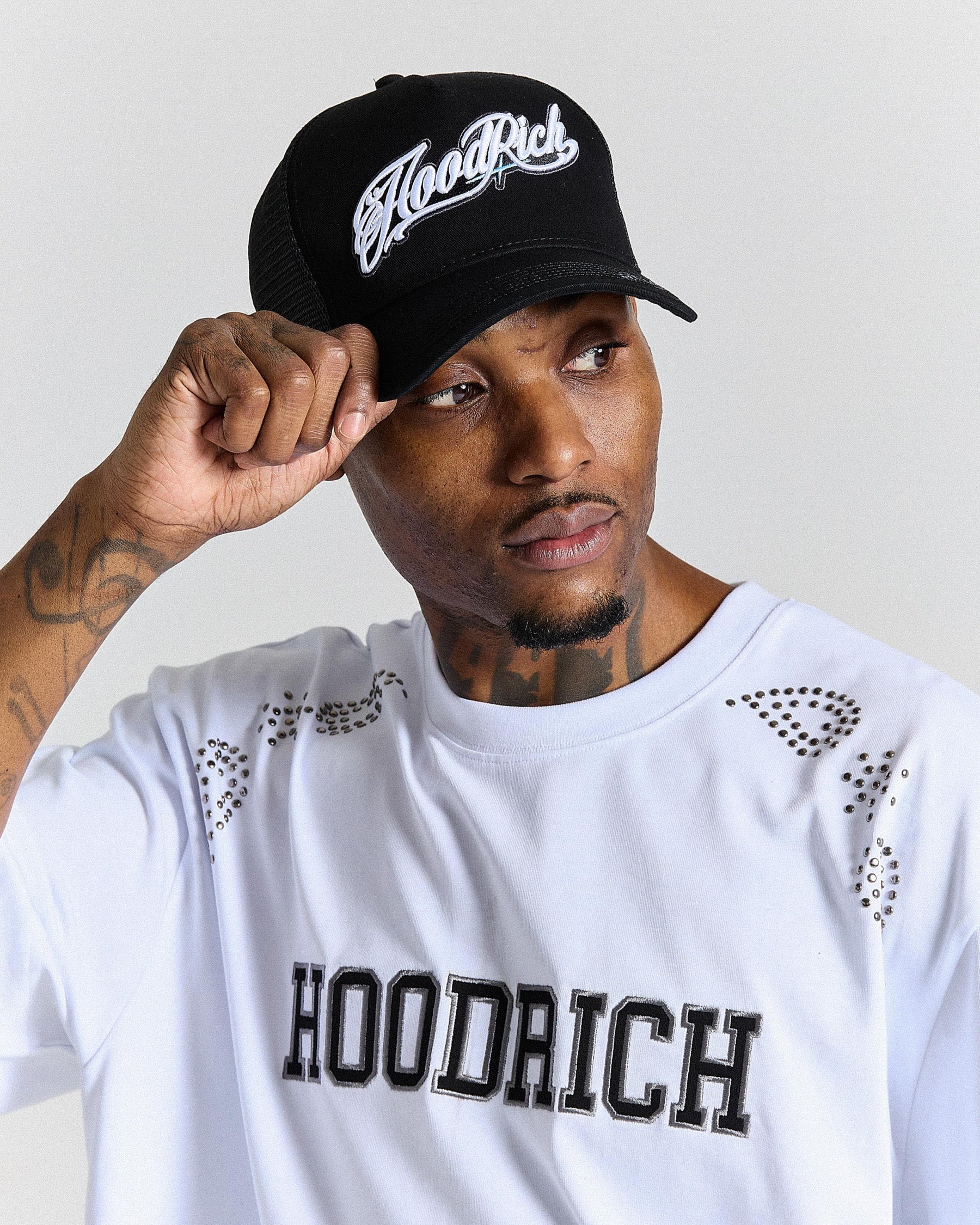 Person wearing a black cap and white shirt with 'Hoodrich' branding.