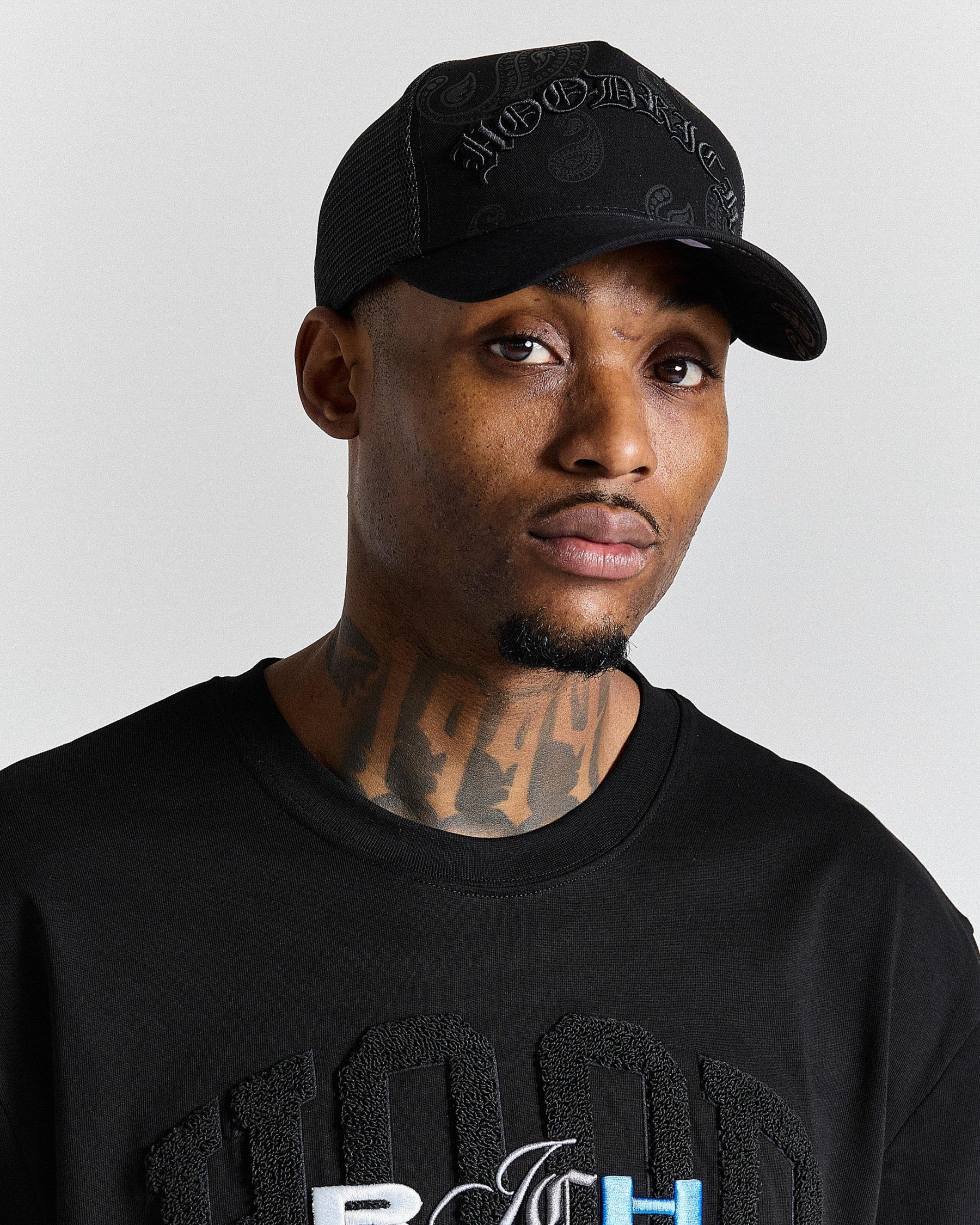 Man wearing a black cap and black shirt with text on a gray background