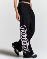 Black pants with white graphic design worn by a person on a light gray background