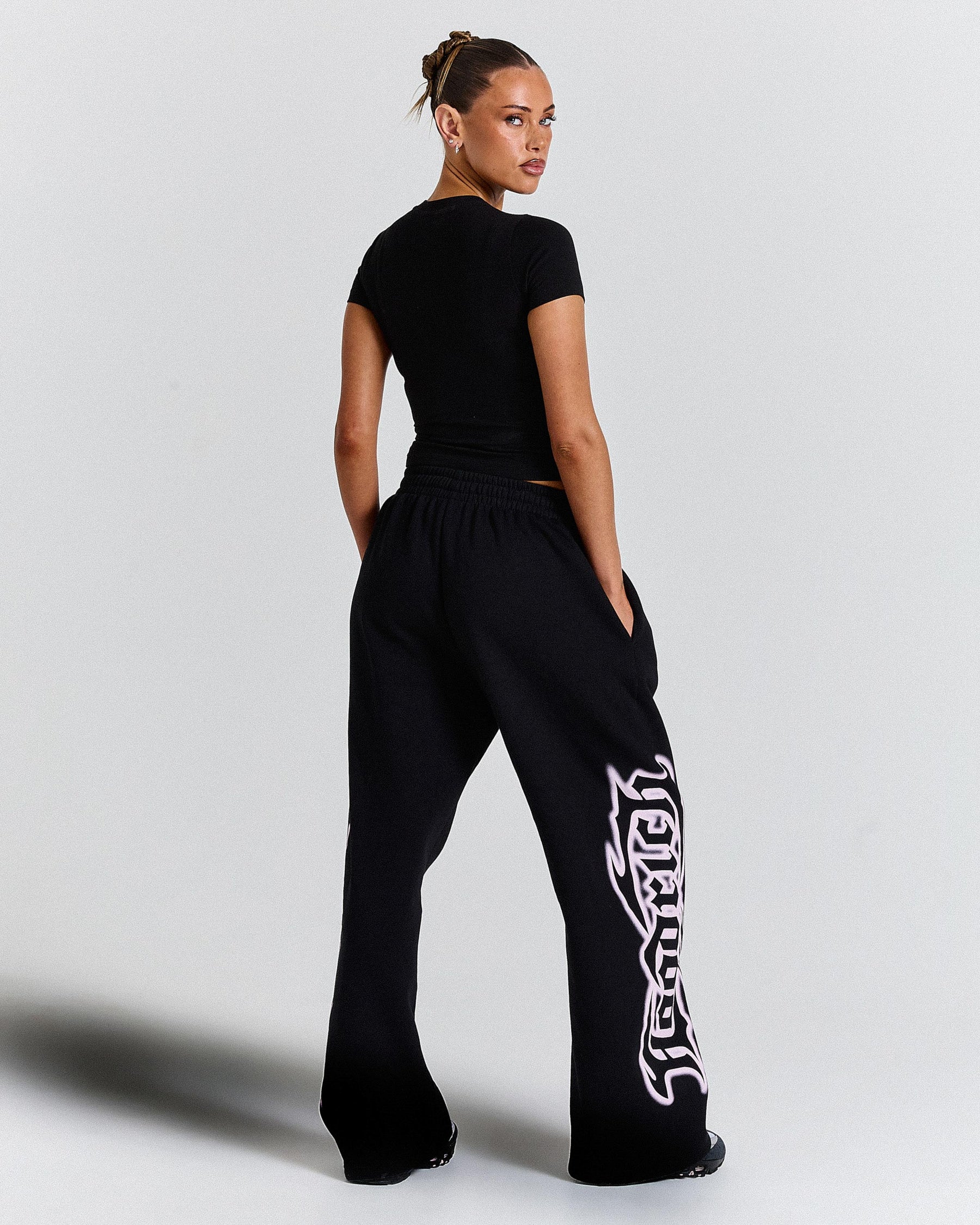 Person wearing black high-waisted pants with a white design on a light gray background