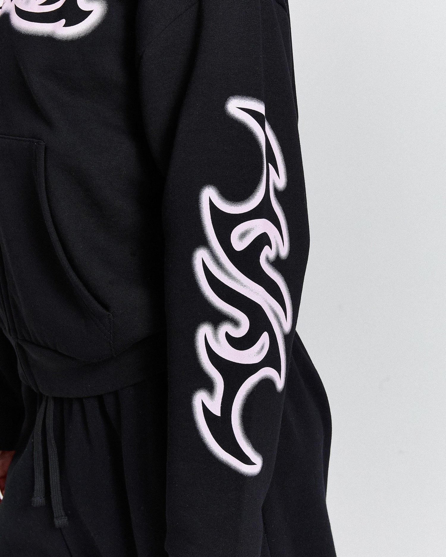 Black garment with white tribal design on sleeve against a light gray background