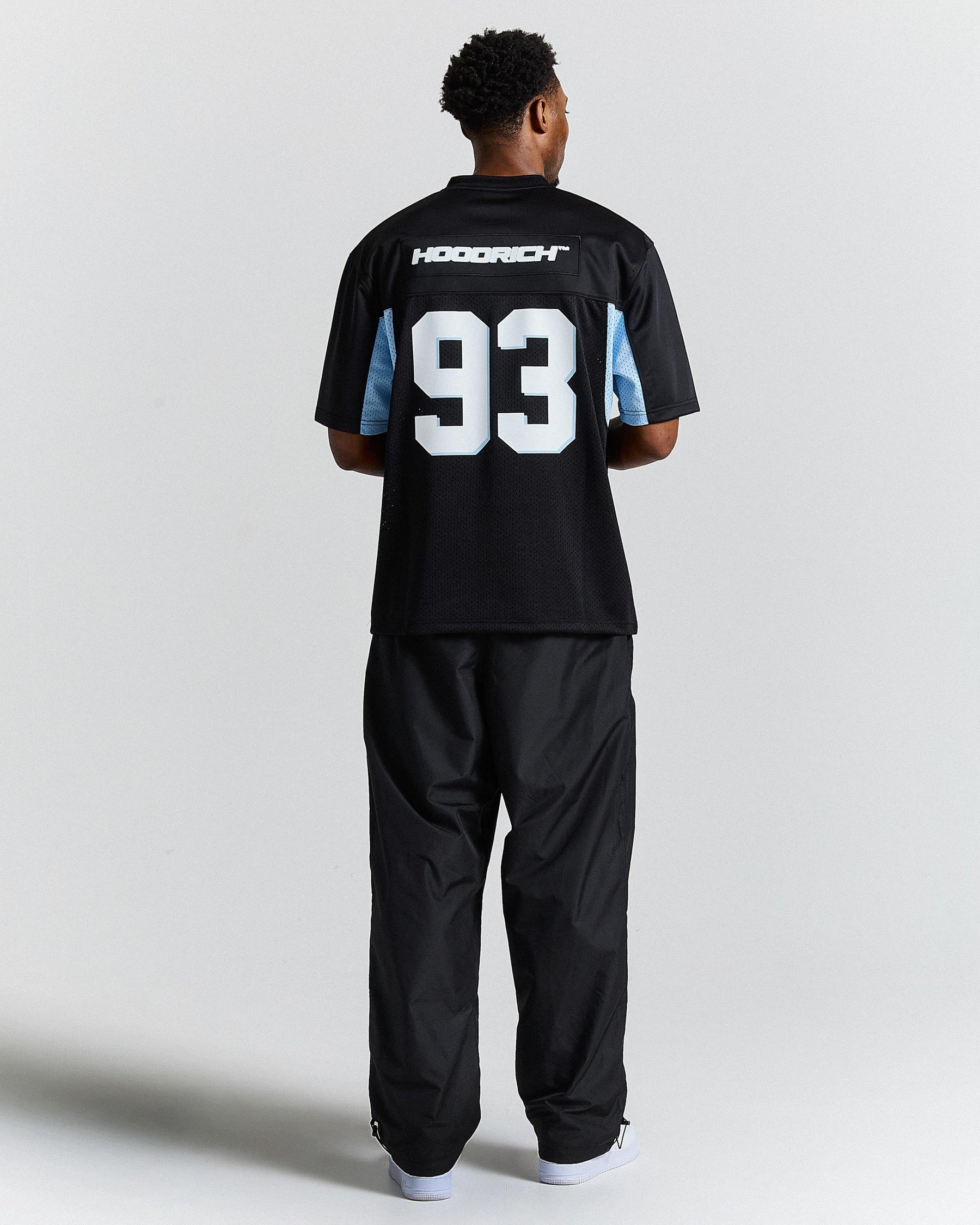 Person wearing a black sports jersey with the number '93' on a plain background