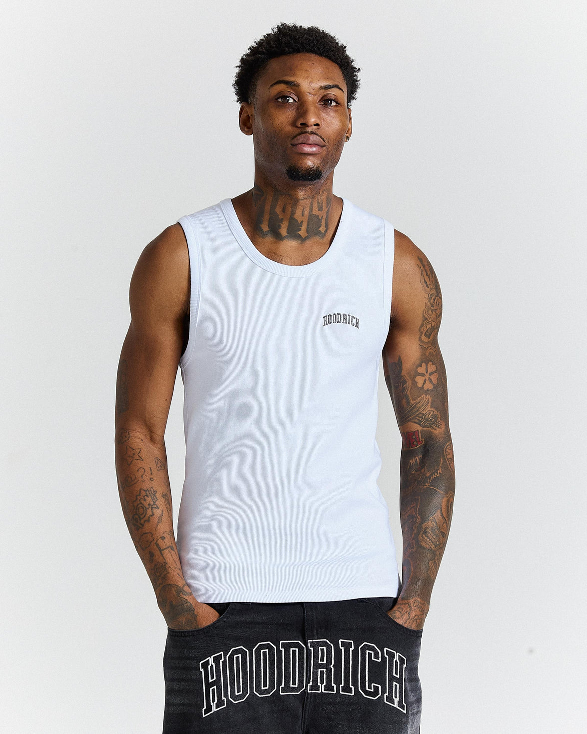 Man wearing a white tank top with 'Hoodrich' branding on a plain background