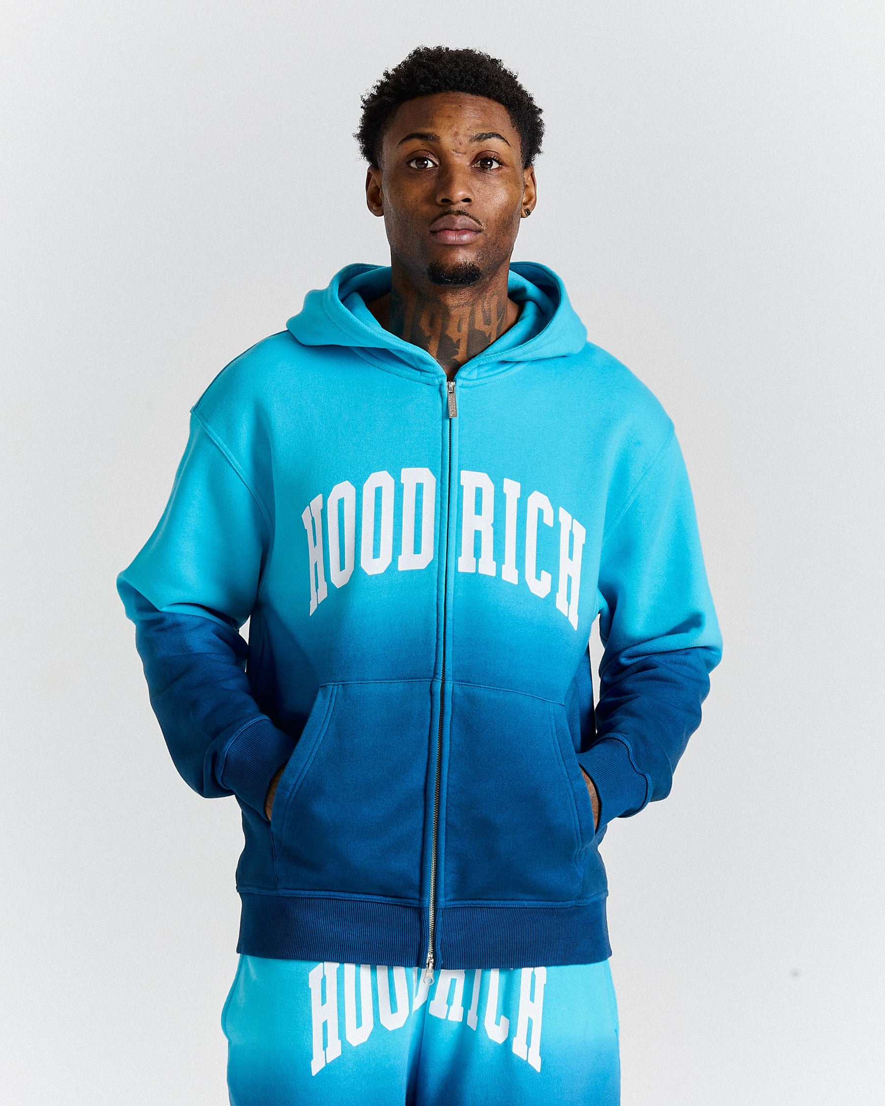Person wearing a blue 'Hood Rich' hoodie and pants on a white background