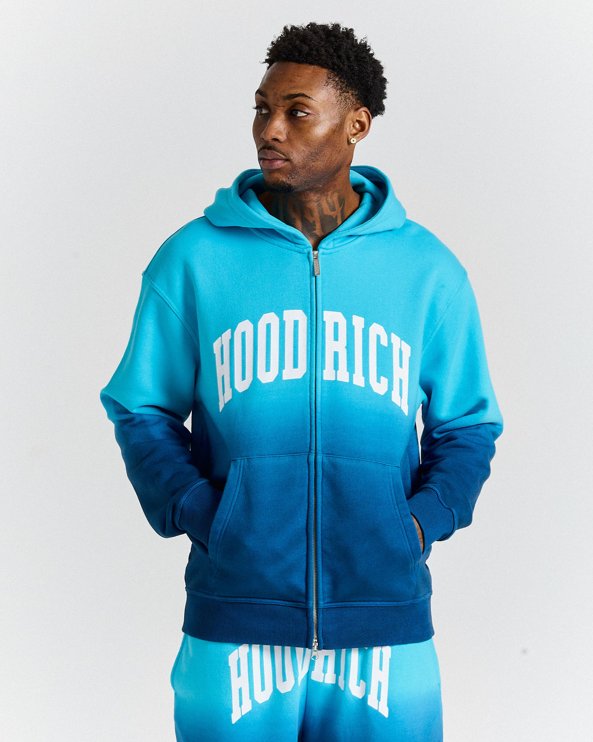 Person wearing a blue 'HOOD RICH' hoodie and shorts on a white background