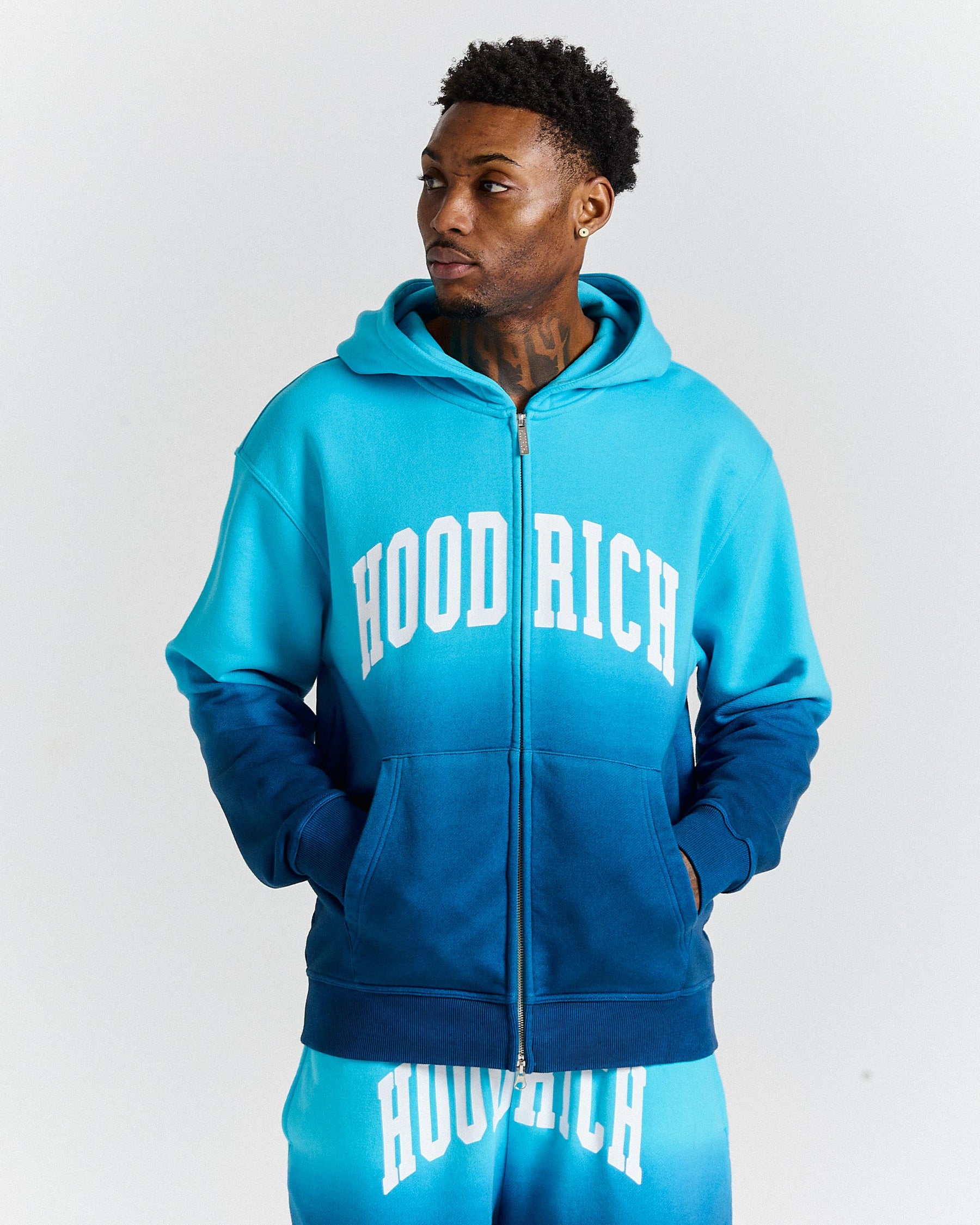 Person wearing a blue 'HOOD RICH' hoodie and shorts on a white background