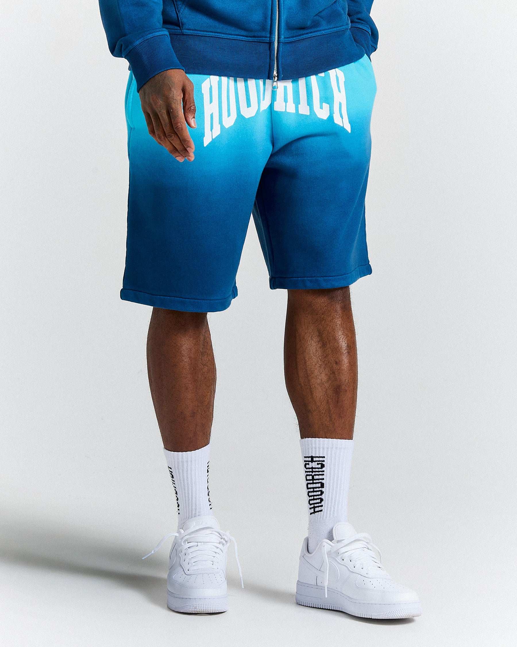 Person wearing blue shorts with 'HOODRICH' branding on a white background