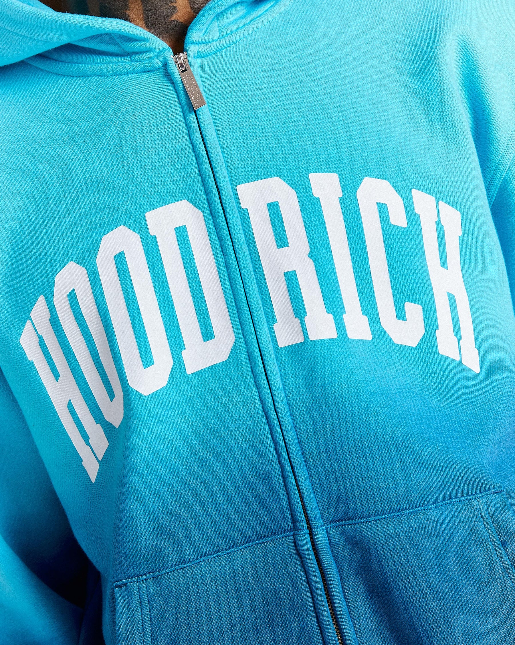 Blue hoodie with 'HOOD RICH' text on a close-up view
