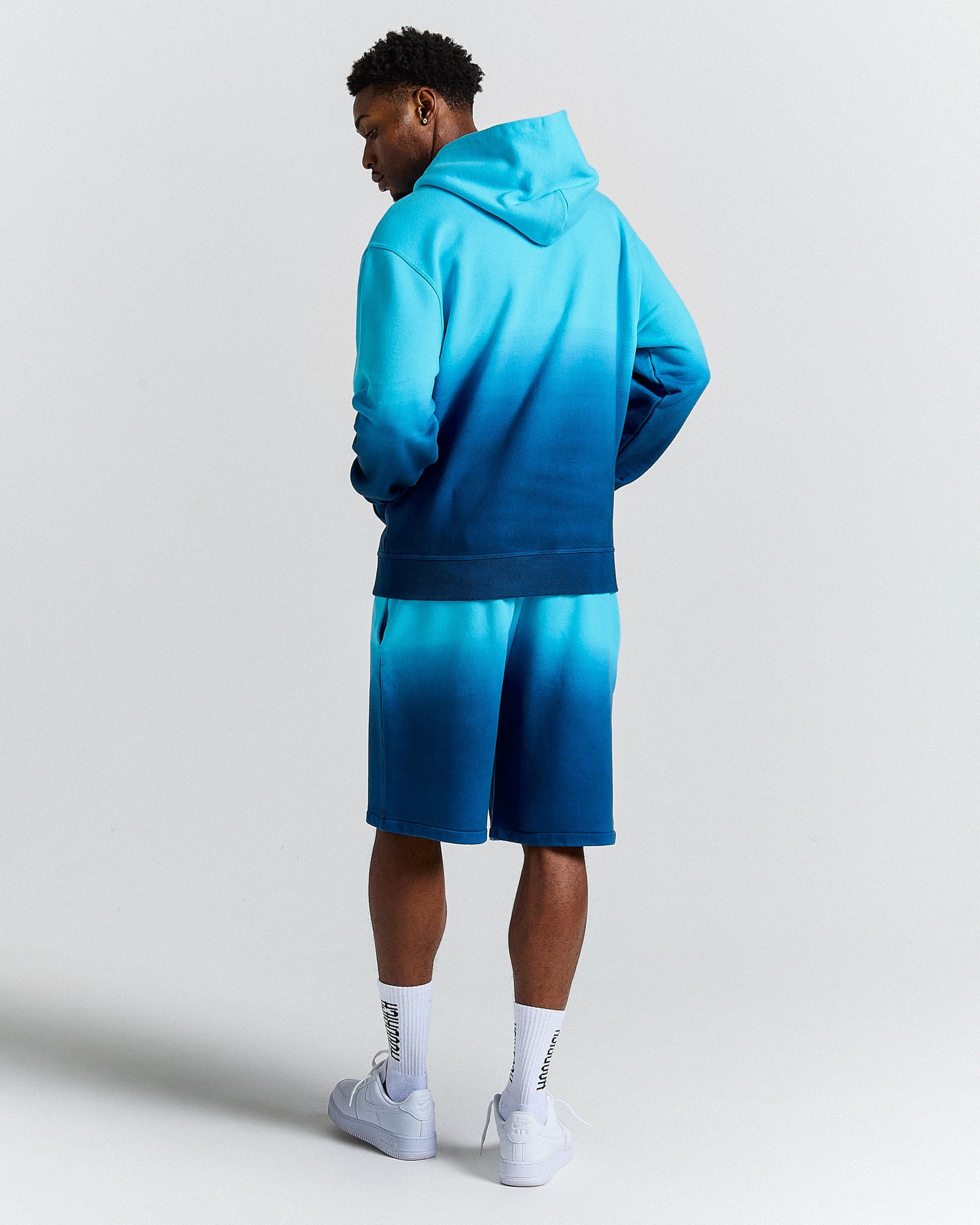 Person wearing a blue gradient hoodie and shorts set on a light gray background