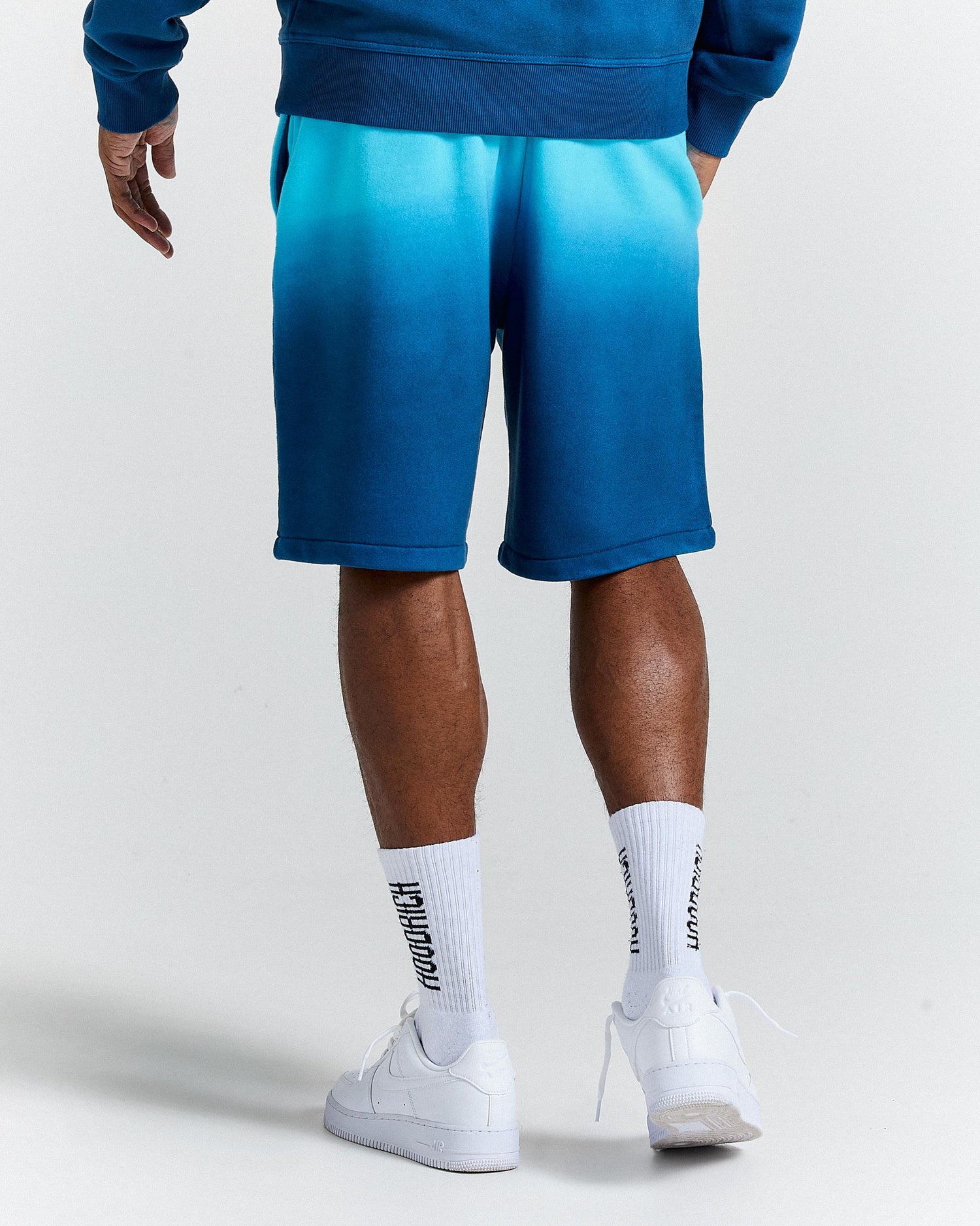 Person wearing blue shorts and white sneakers on a light gray background