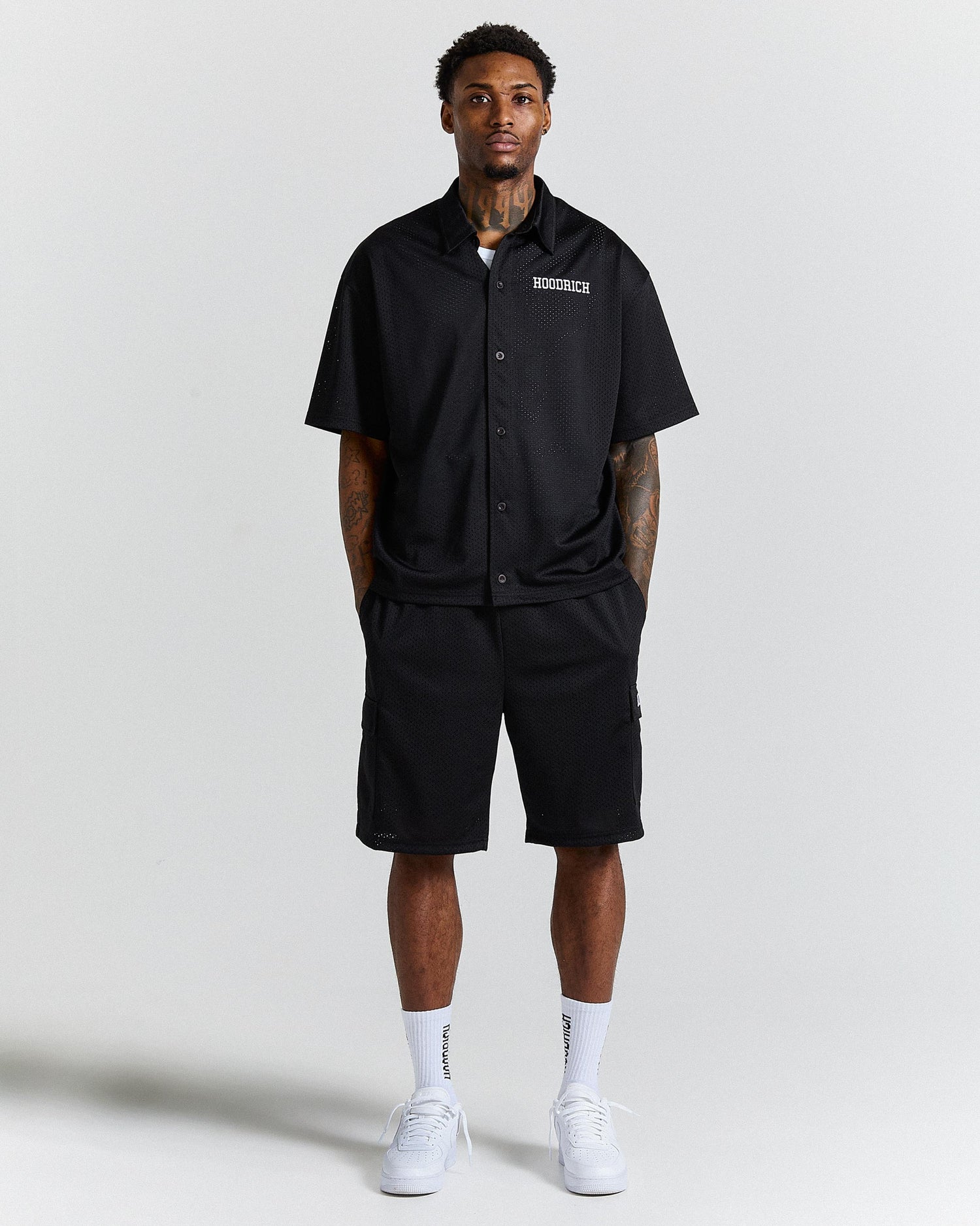 Person wearing a black shirt and shorts with visible branding on a white background