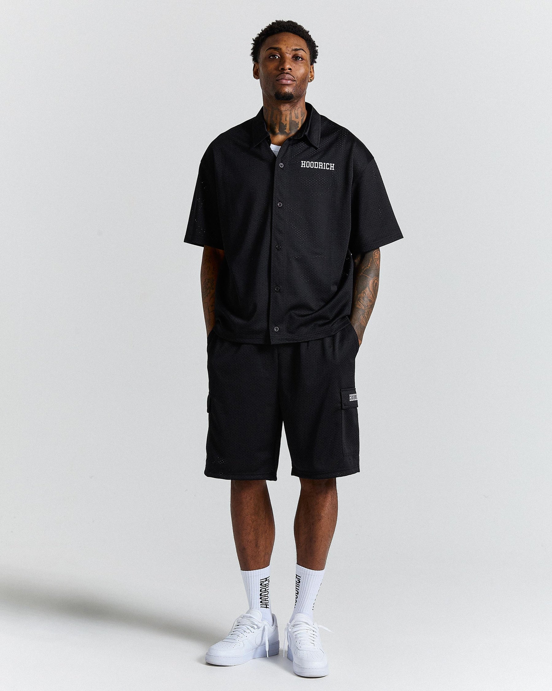 Person wearing a black shirt and shorts with visible branding on a plain background