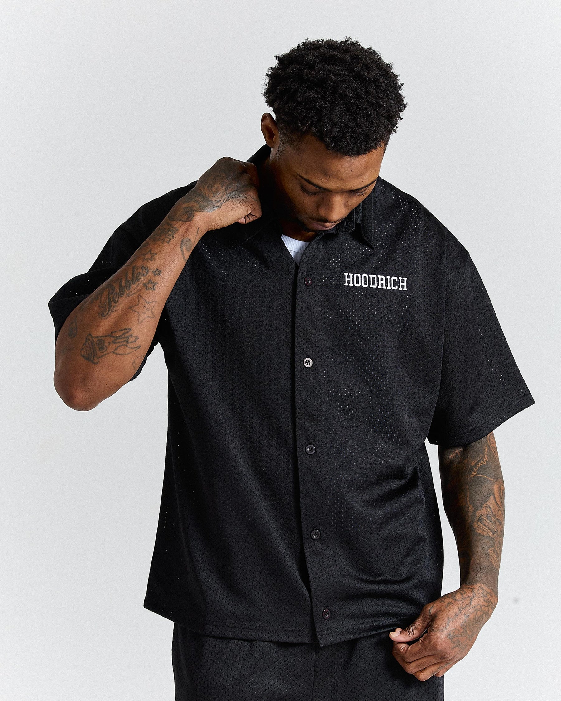 Man wearing a black 'Hoodrich' shirt on a white background